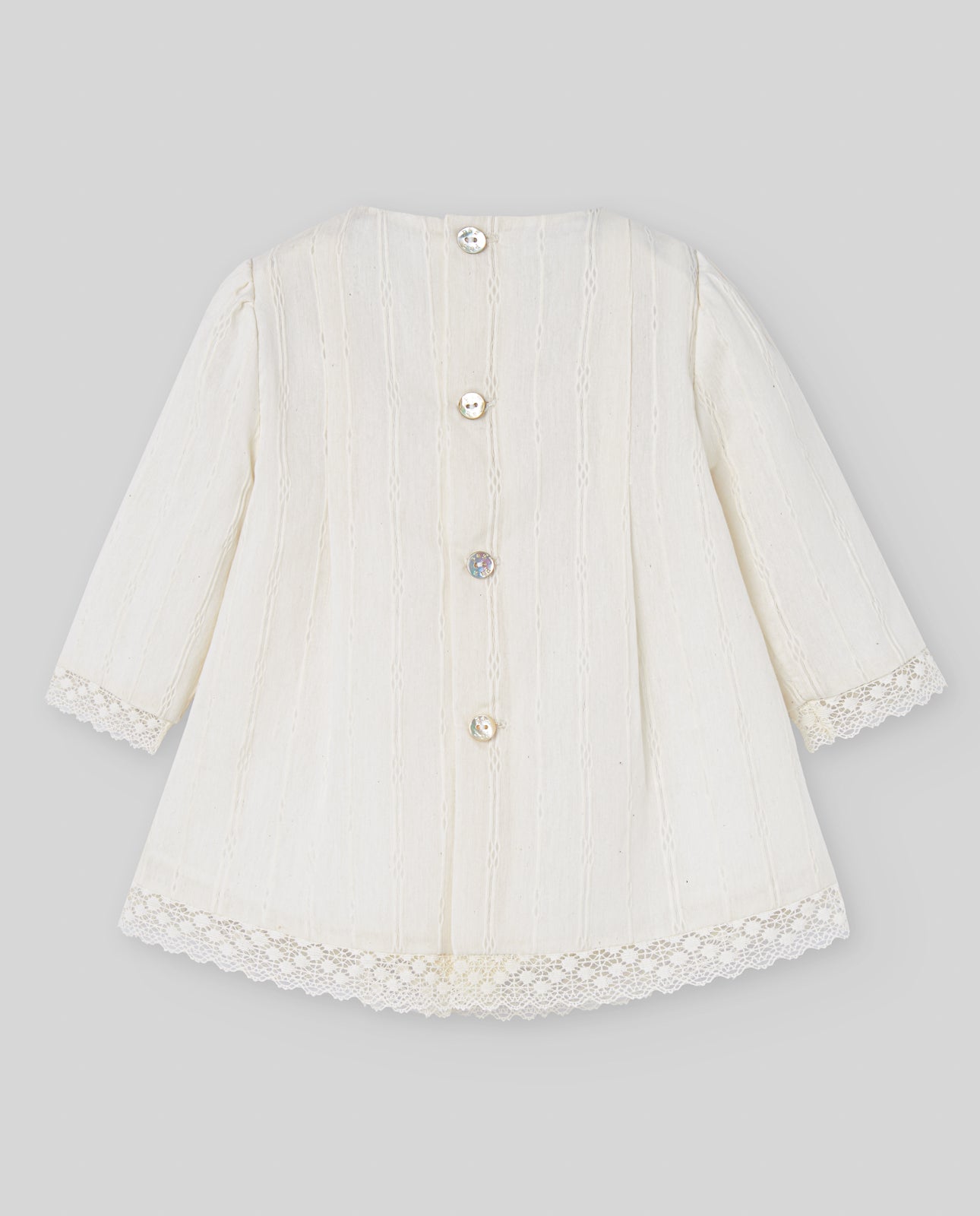 White baby coat with lace details on a gray background