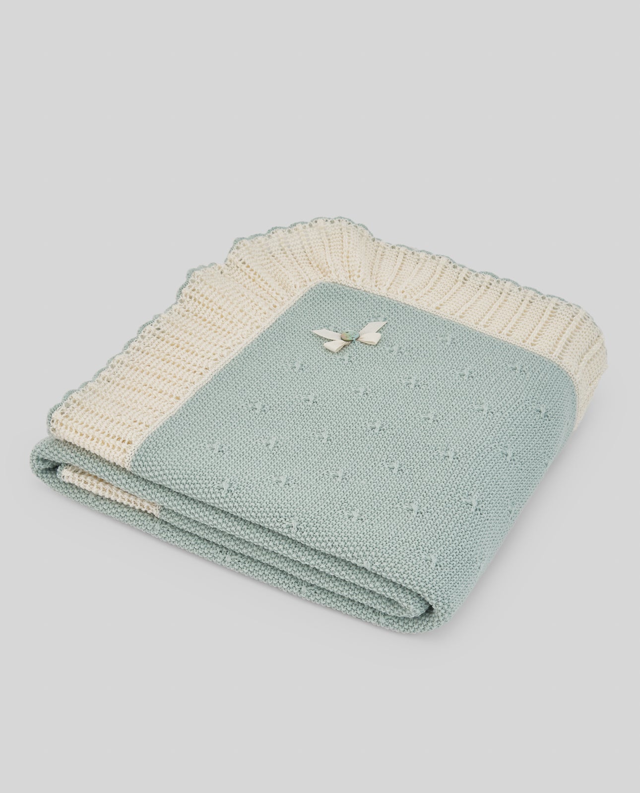 Folded teal and beige blanket on a light gray background
