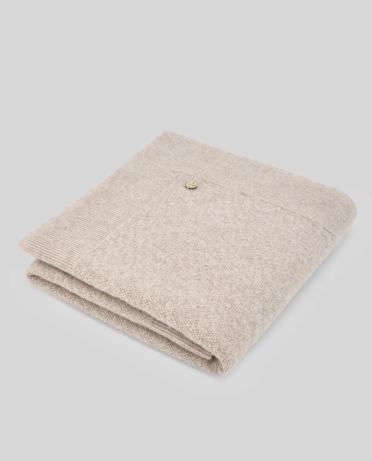 Folded beige blanket on a light gray background