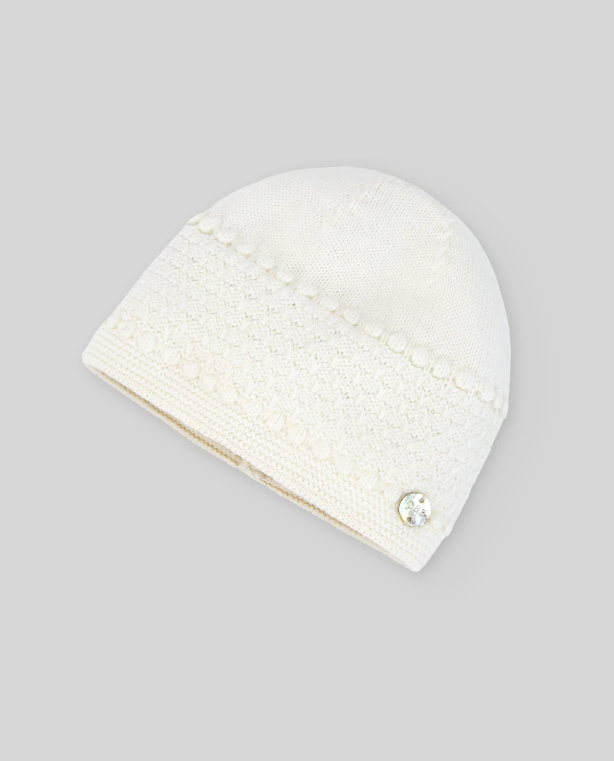 White knit beanie with a decorative button on a gray background