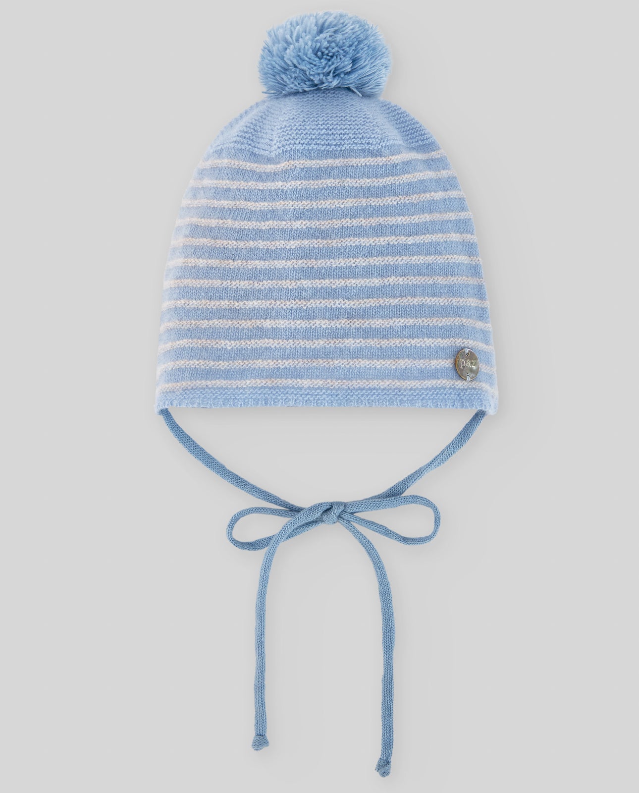 Blue striped knit baby hat with pom-pom on a light gray background