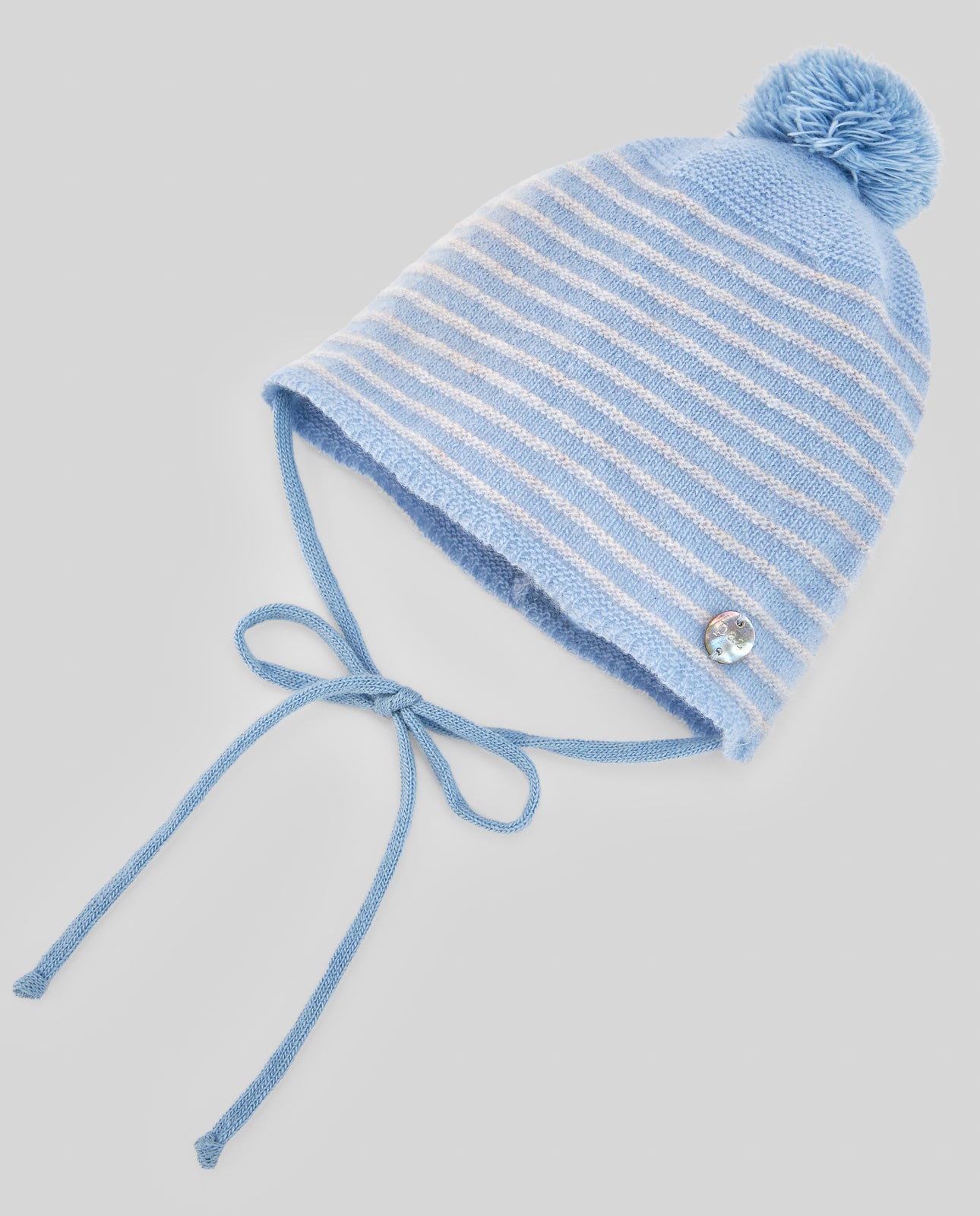 Blue striped knit baby hat with a pom-pom on a light gray background