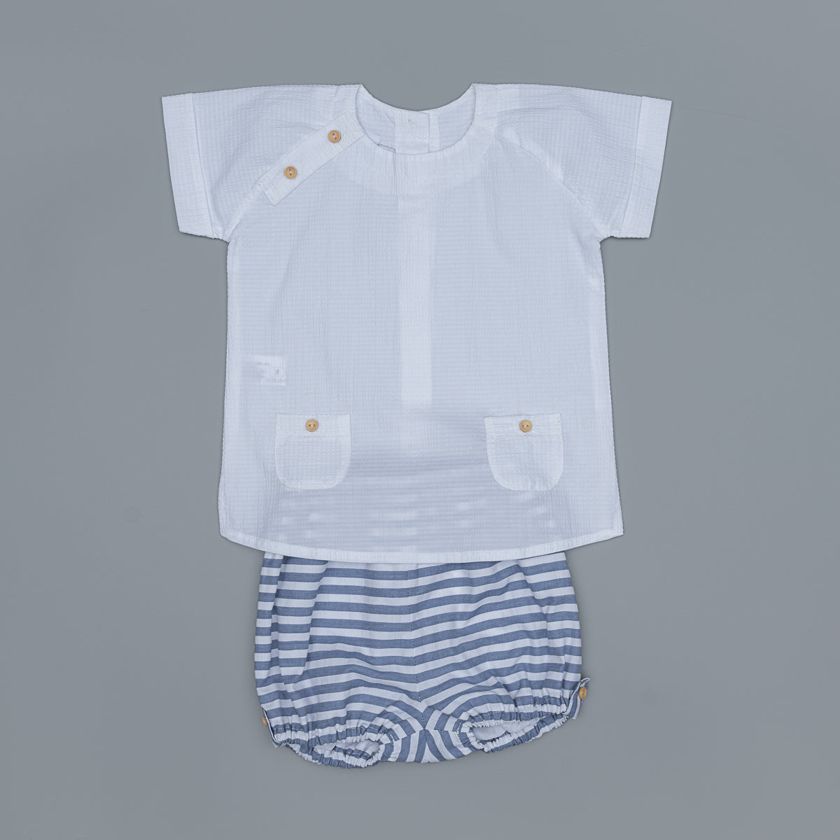 White shirt with button details and striped shorts on a gray background