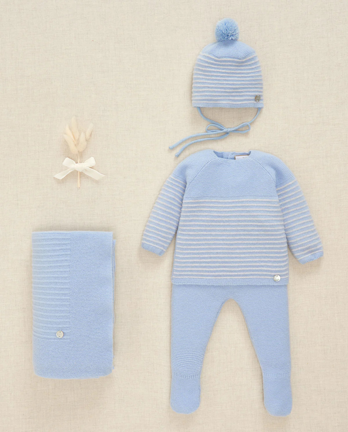 Blue baby outfit with striped sweater, pants, and hat on a beige background