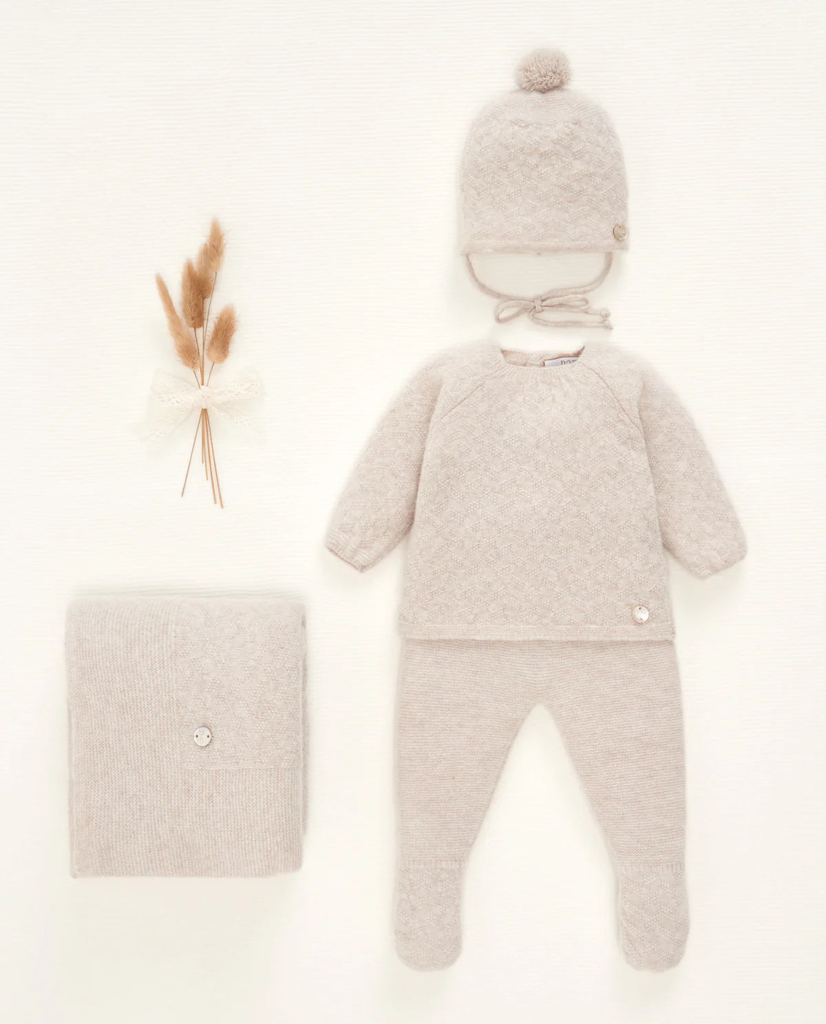 Baby outfit with knitted hat and blanket on a light background