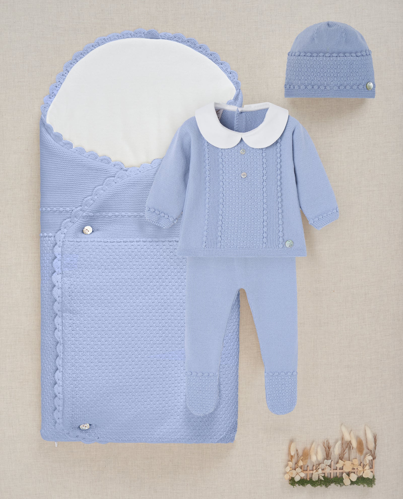 Blue baby outfit with matching hat on a beige background