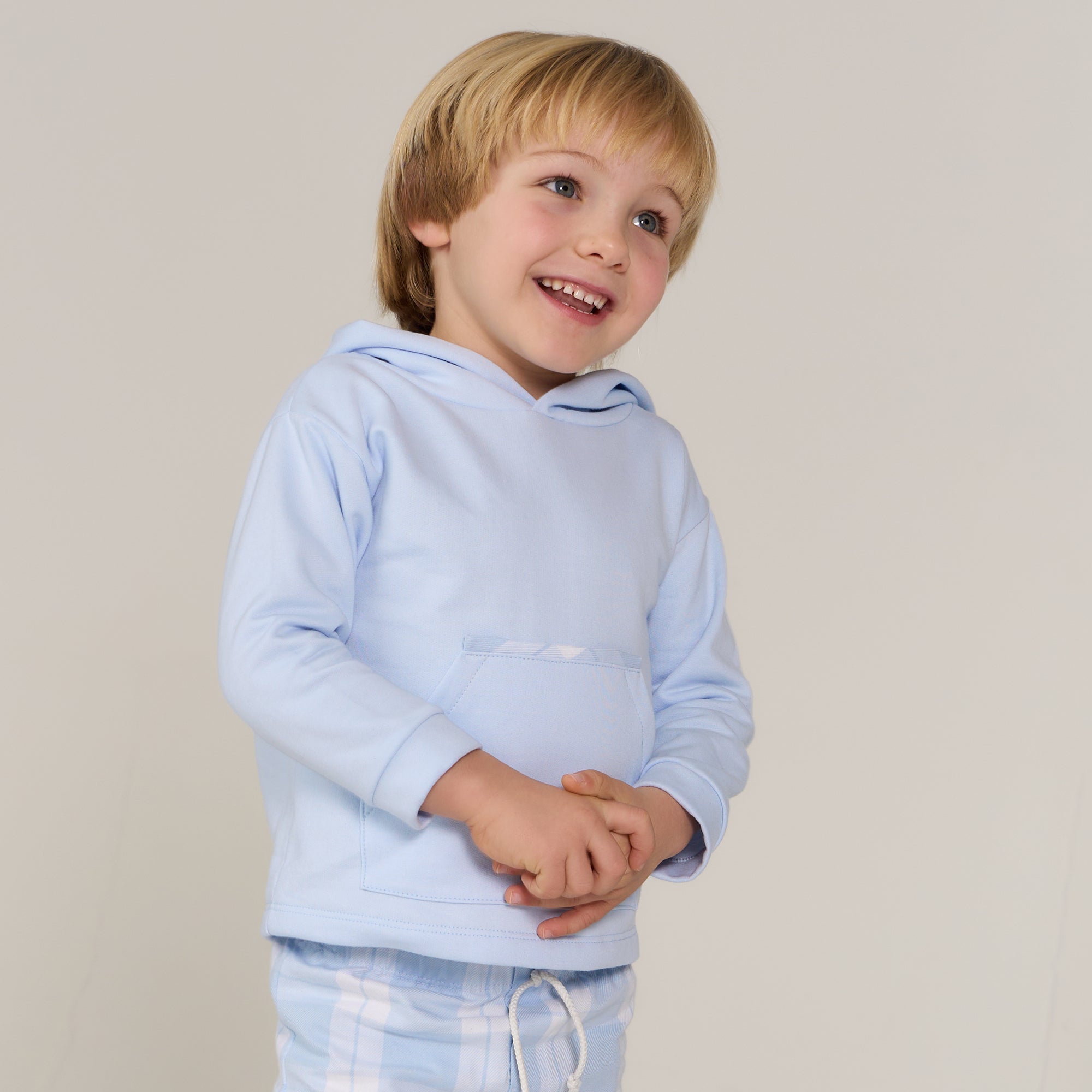 Child wearing a light blue hoodie against a plain background
