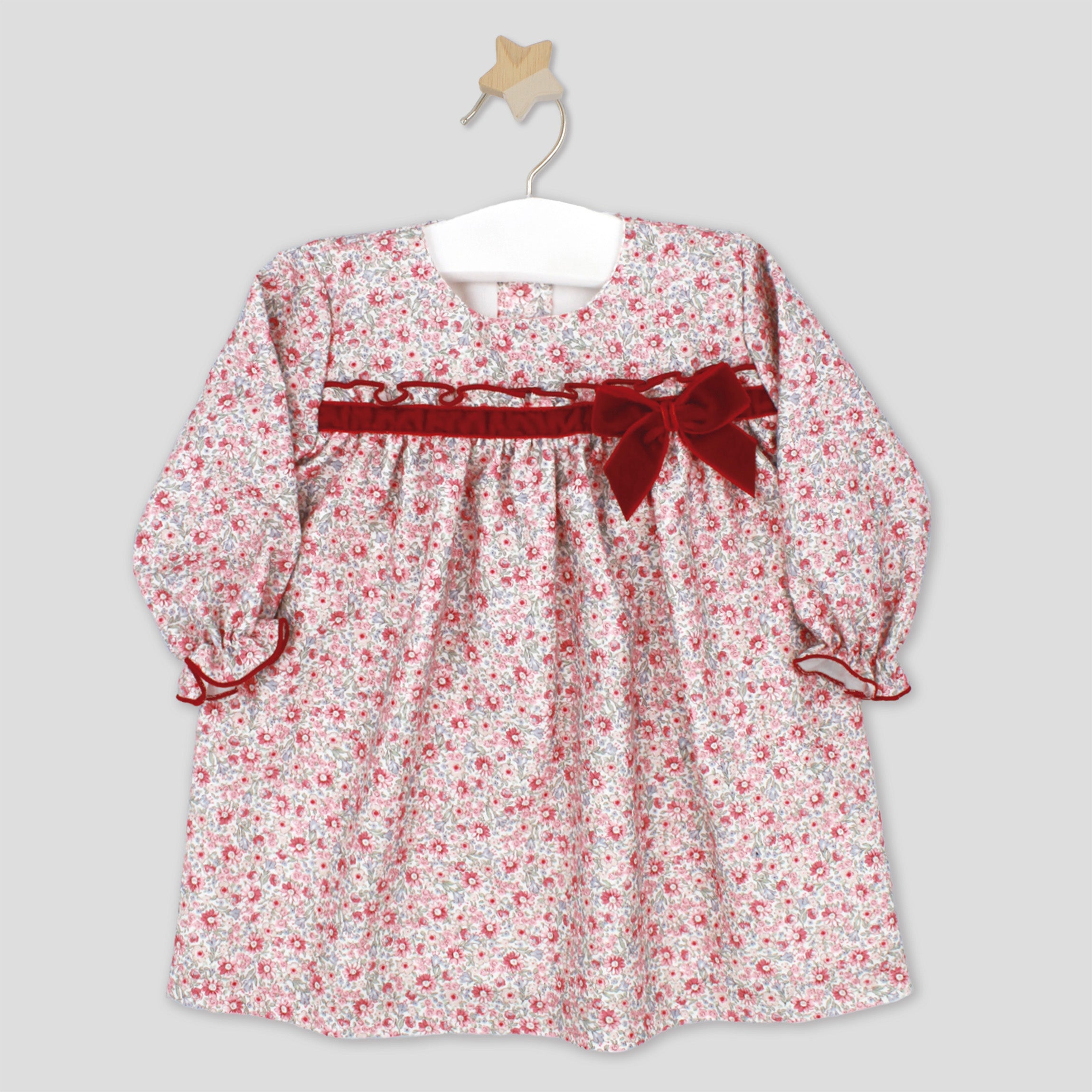 Floral dress with a red ribbon on a hanger against a gray background