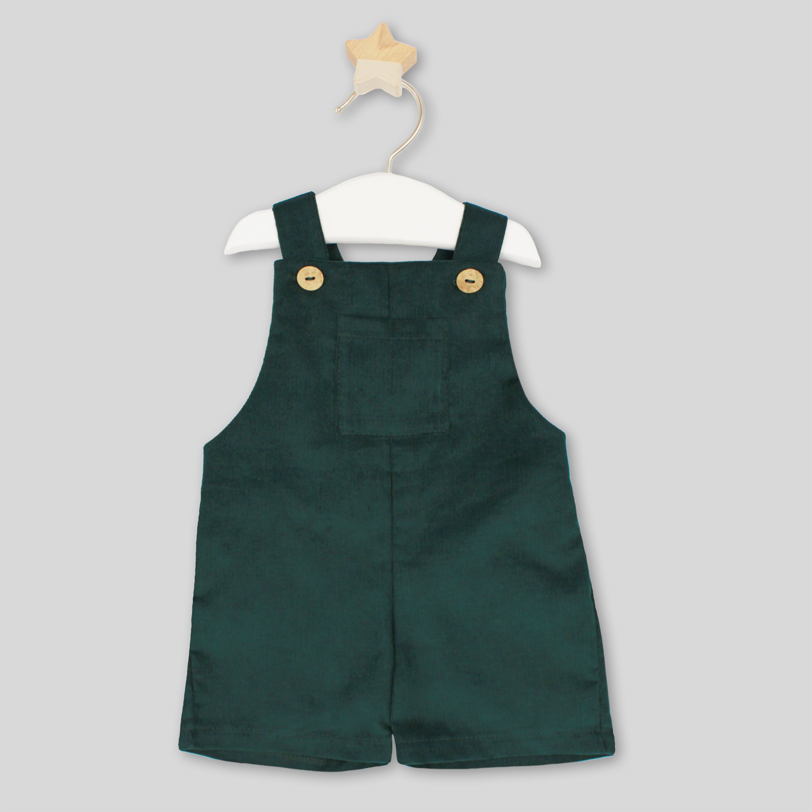 Green children's overalls on a hanger against a light gray background
