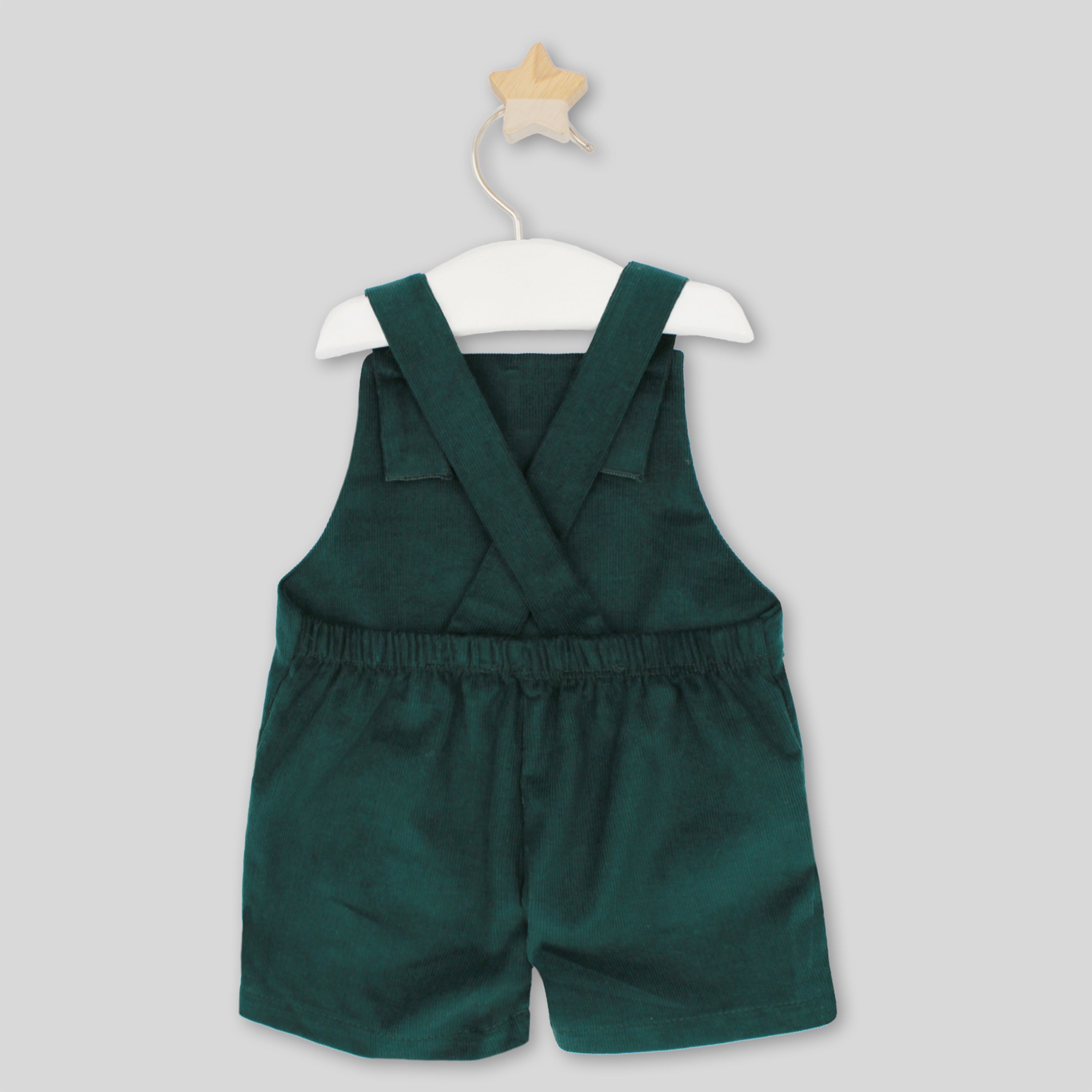 Green children's overalls on a white hanger against a light gray background