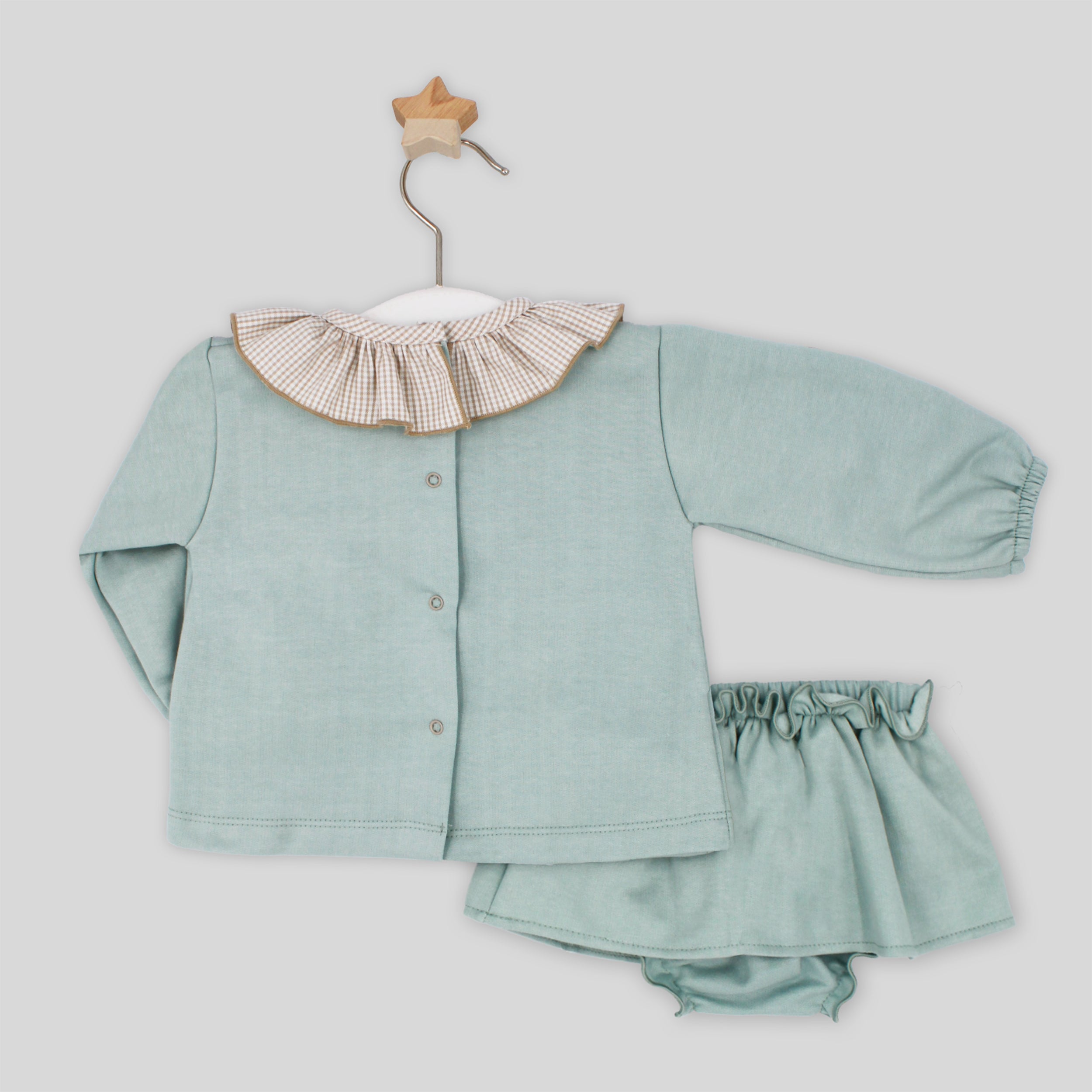 Children's green outfit with ruffled collar on a light gray background