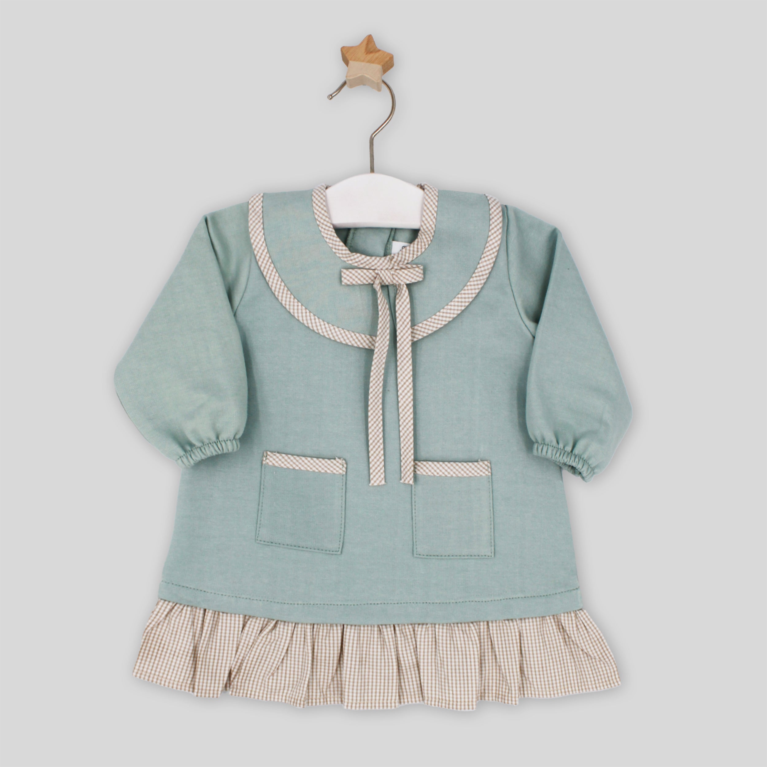 Children's dress with a bow on a hanger against a light gray background
