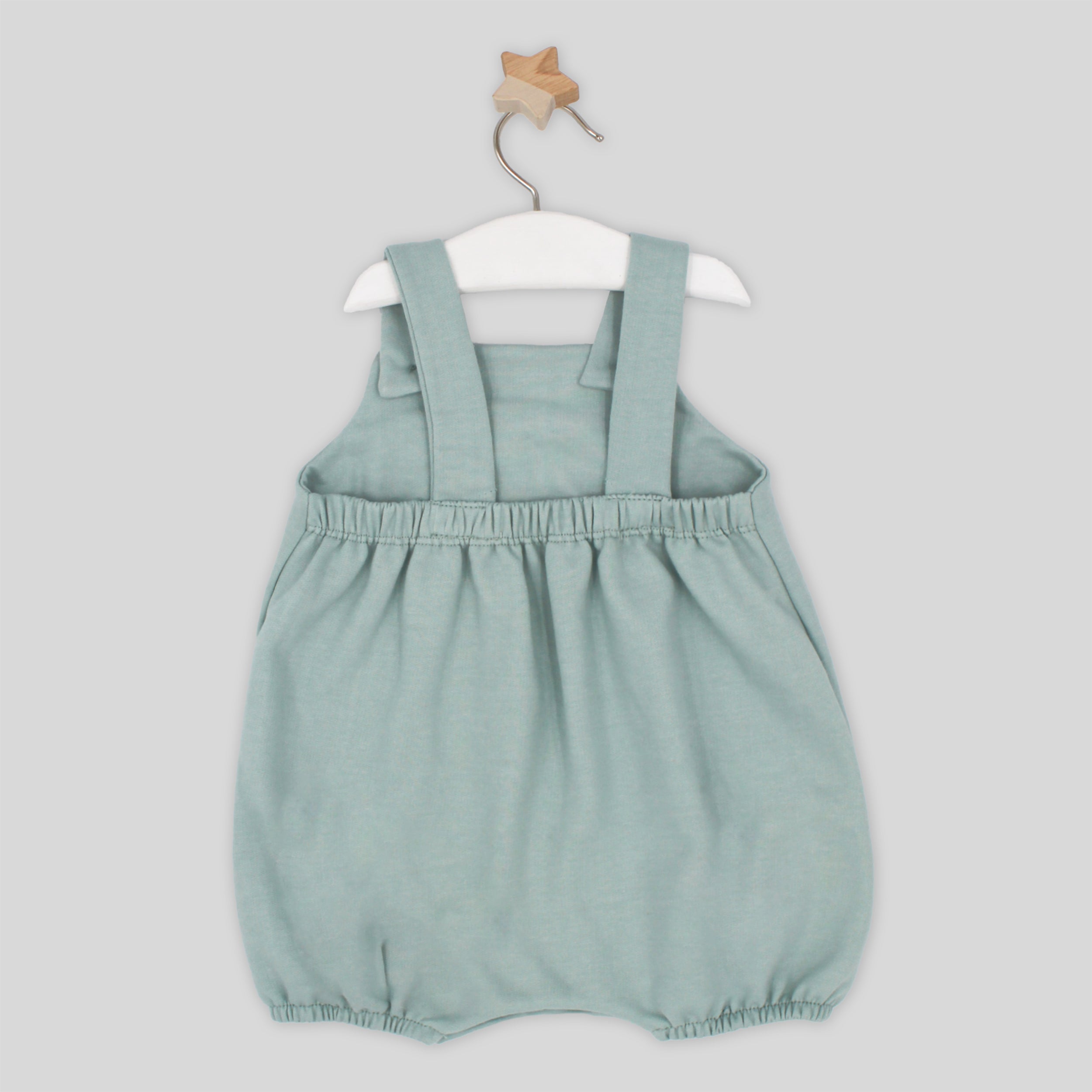 Light blue baby romper with straps on a white hanger against a light gray background