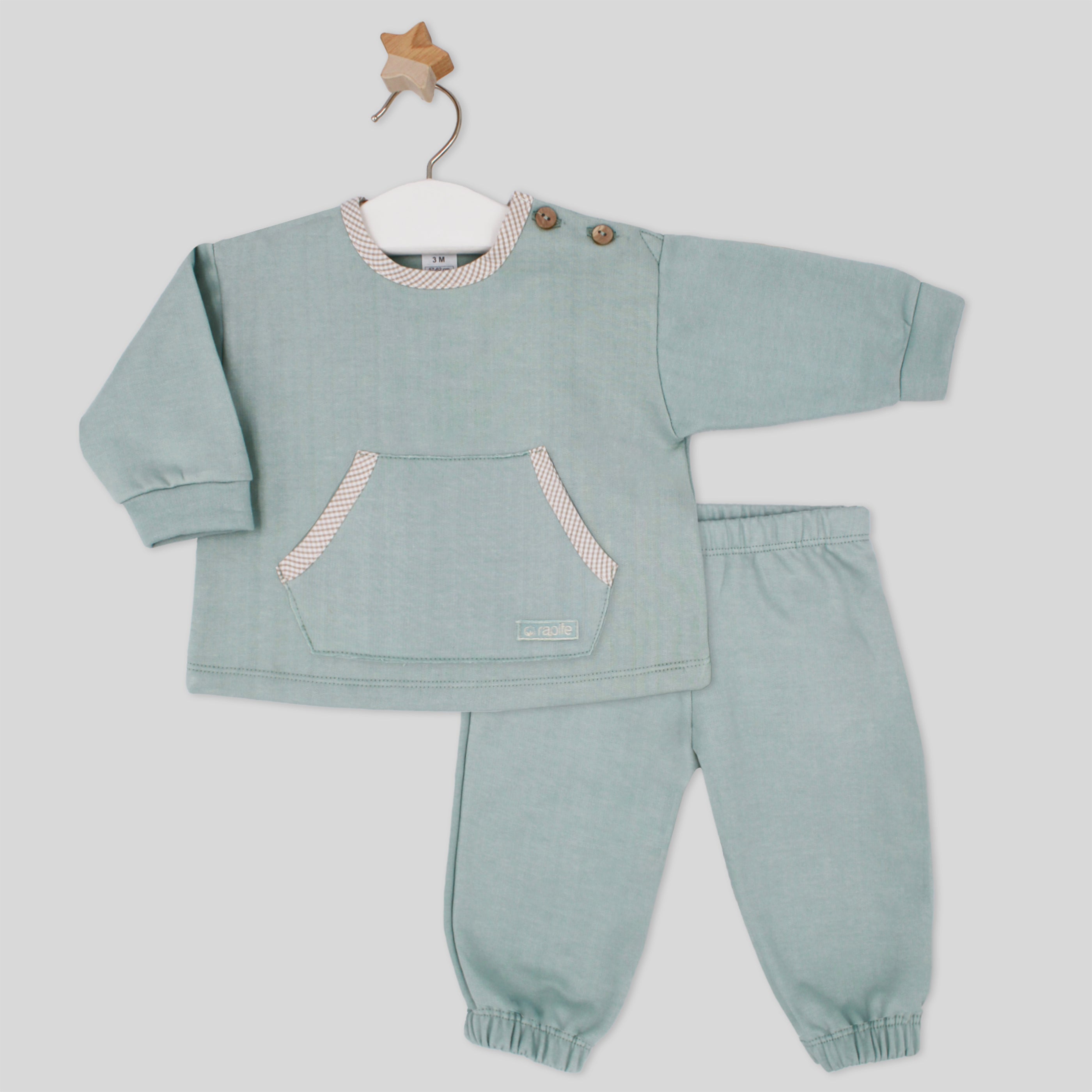 Children's green outfit with a sweatshirt and pants on a hanger against a light gray background