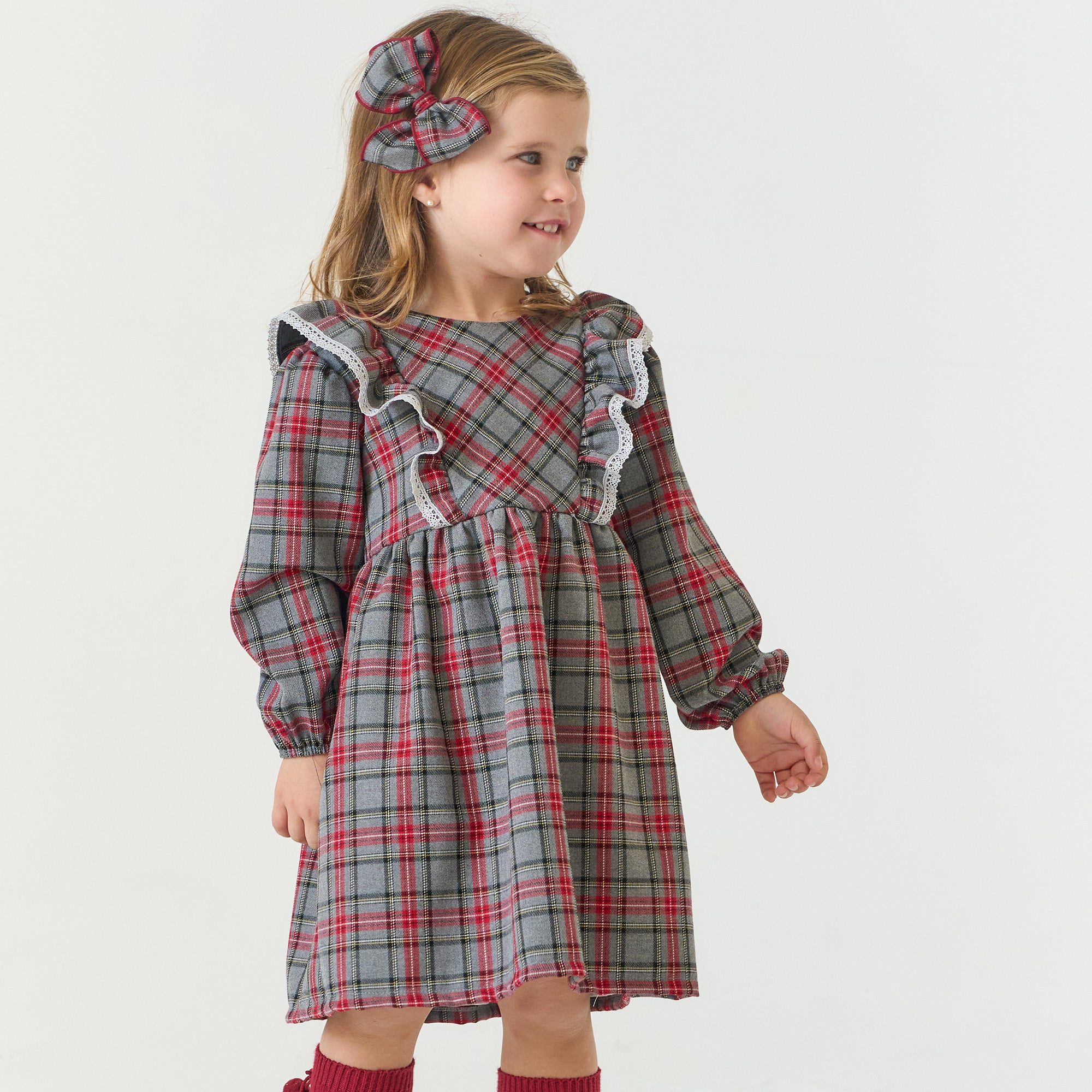 Young girl wearing a plaid dress with ruffled details on a white background