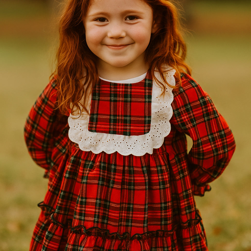 Young girl wearing a red plaid dress with a white collar in an outdoor setting