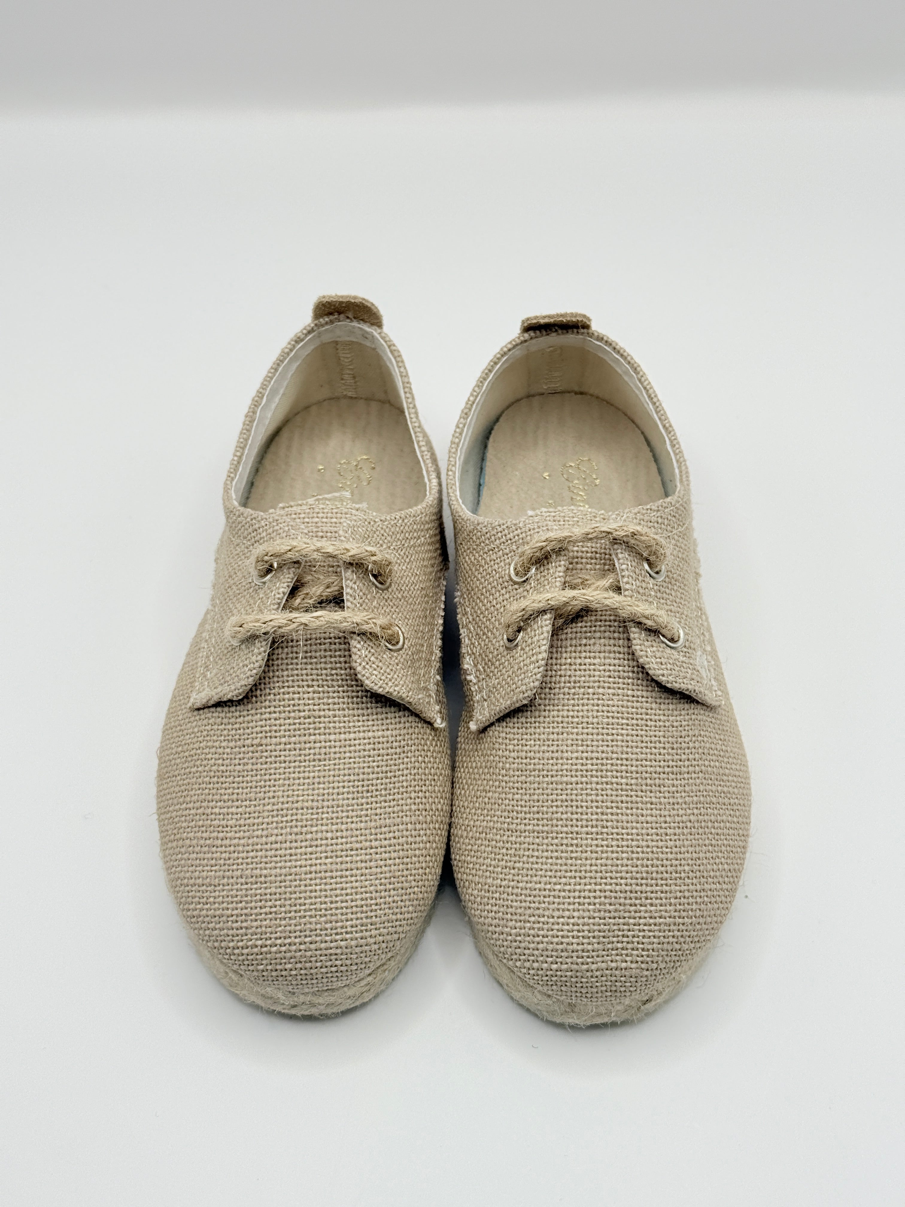 Pair of beige children's shoes on a light gray background