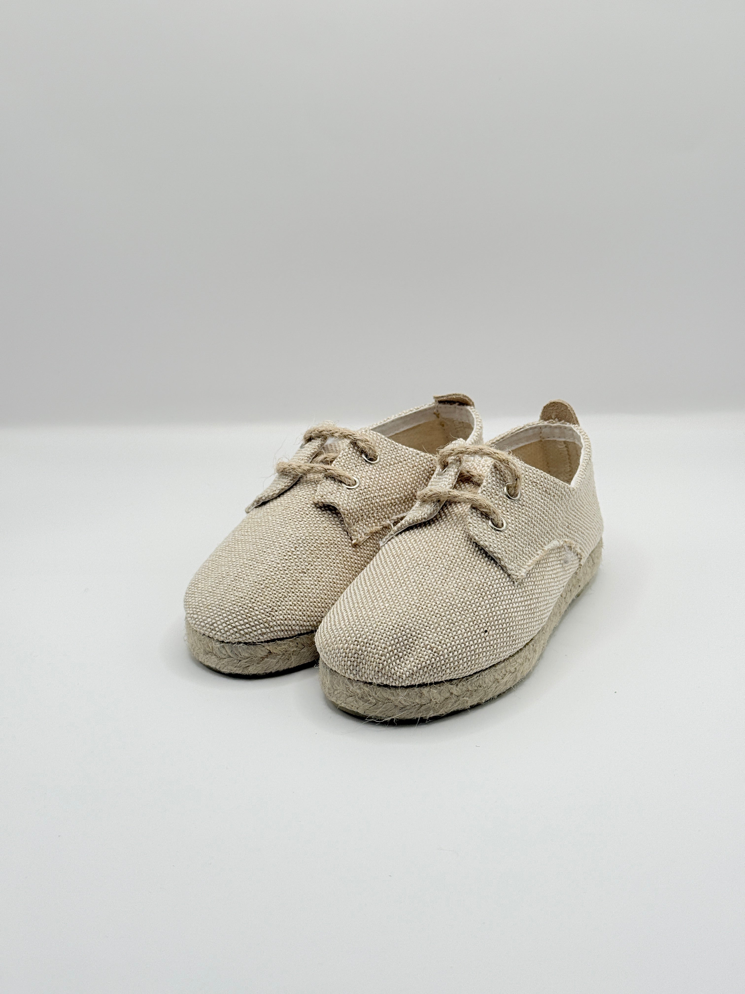 Pair of beige baby shoes on a white background