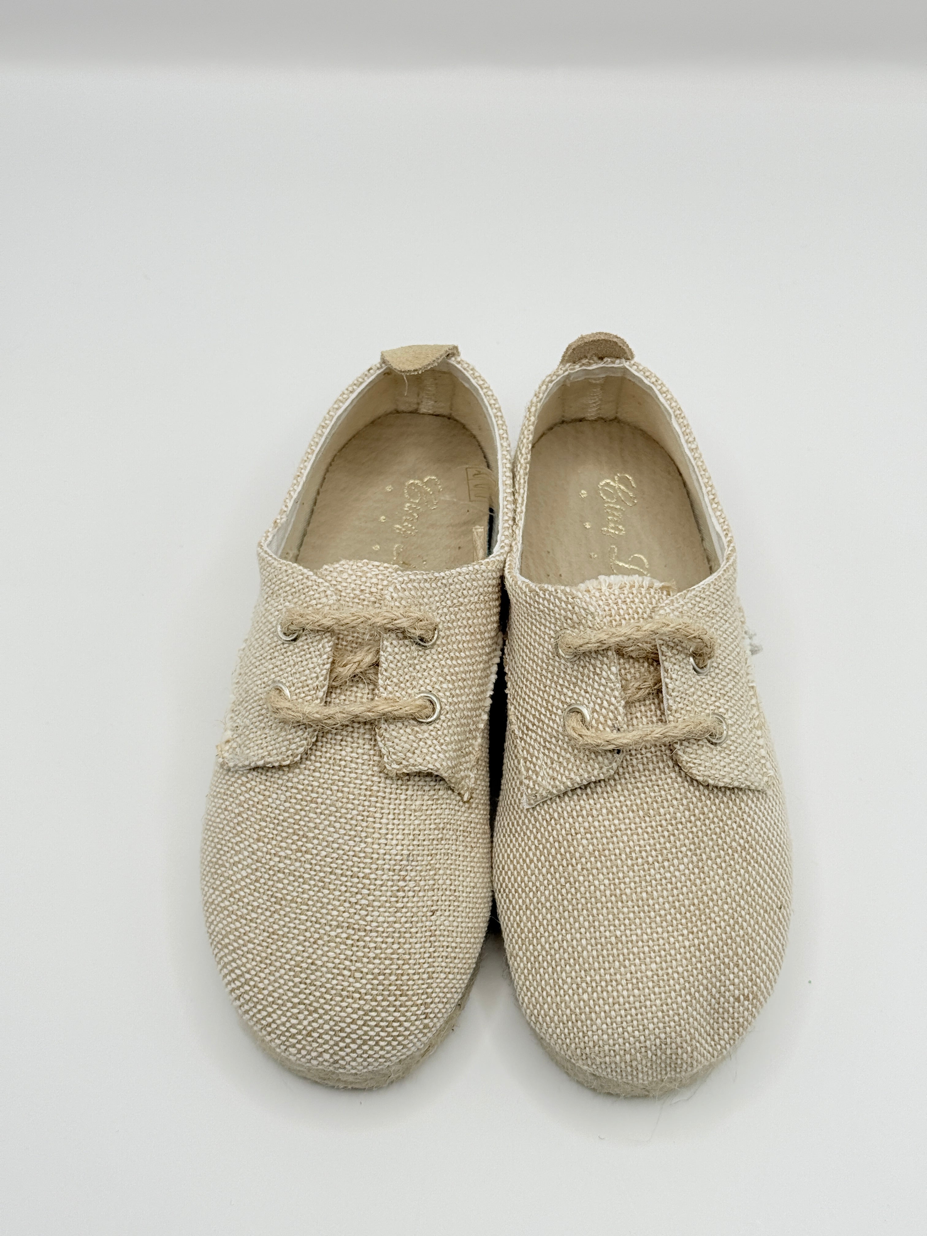 Pair of beige knit shoes on a light gray background