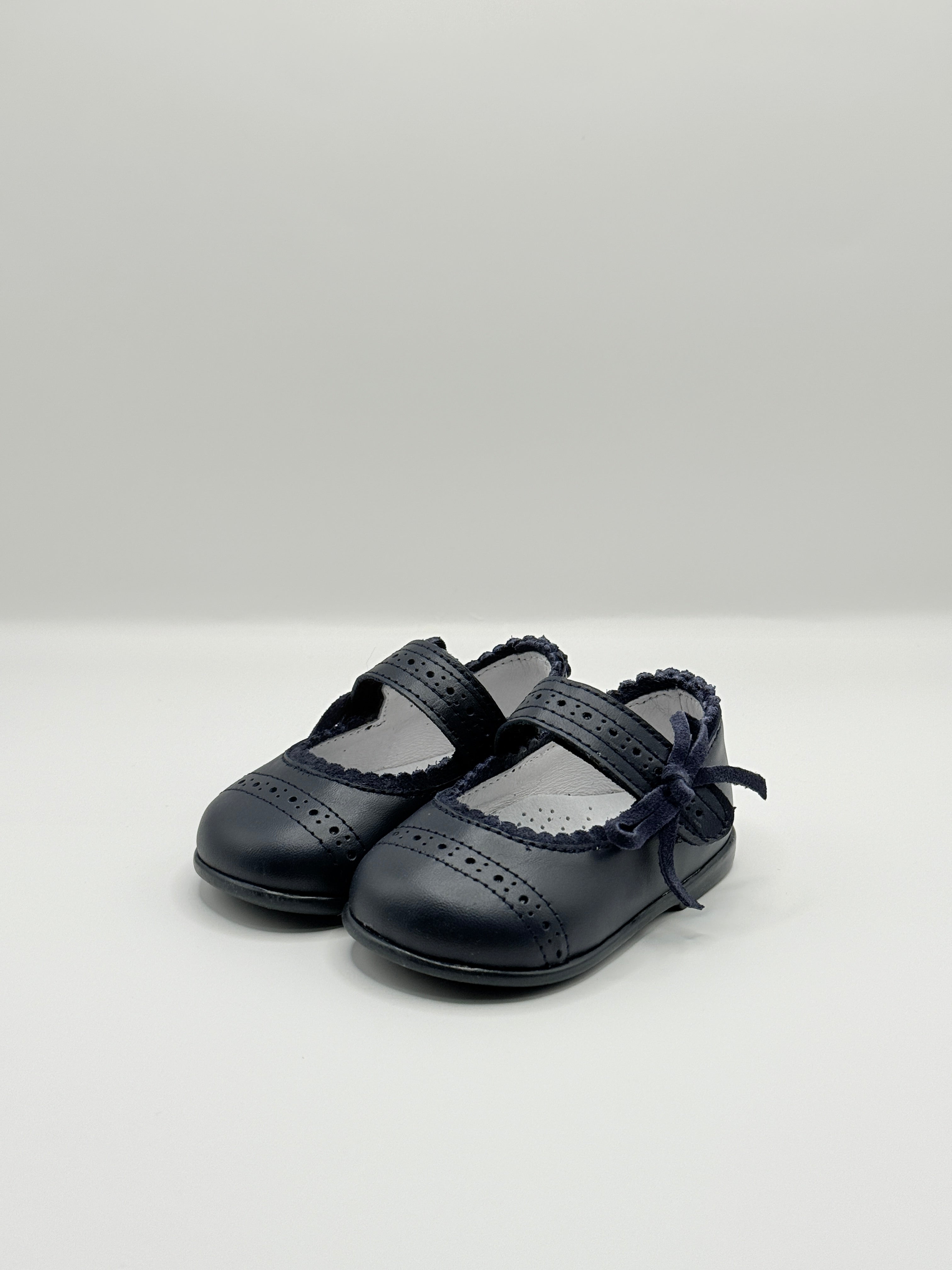 Black leather shoes with criss-cross design on a light gray background