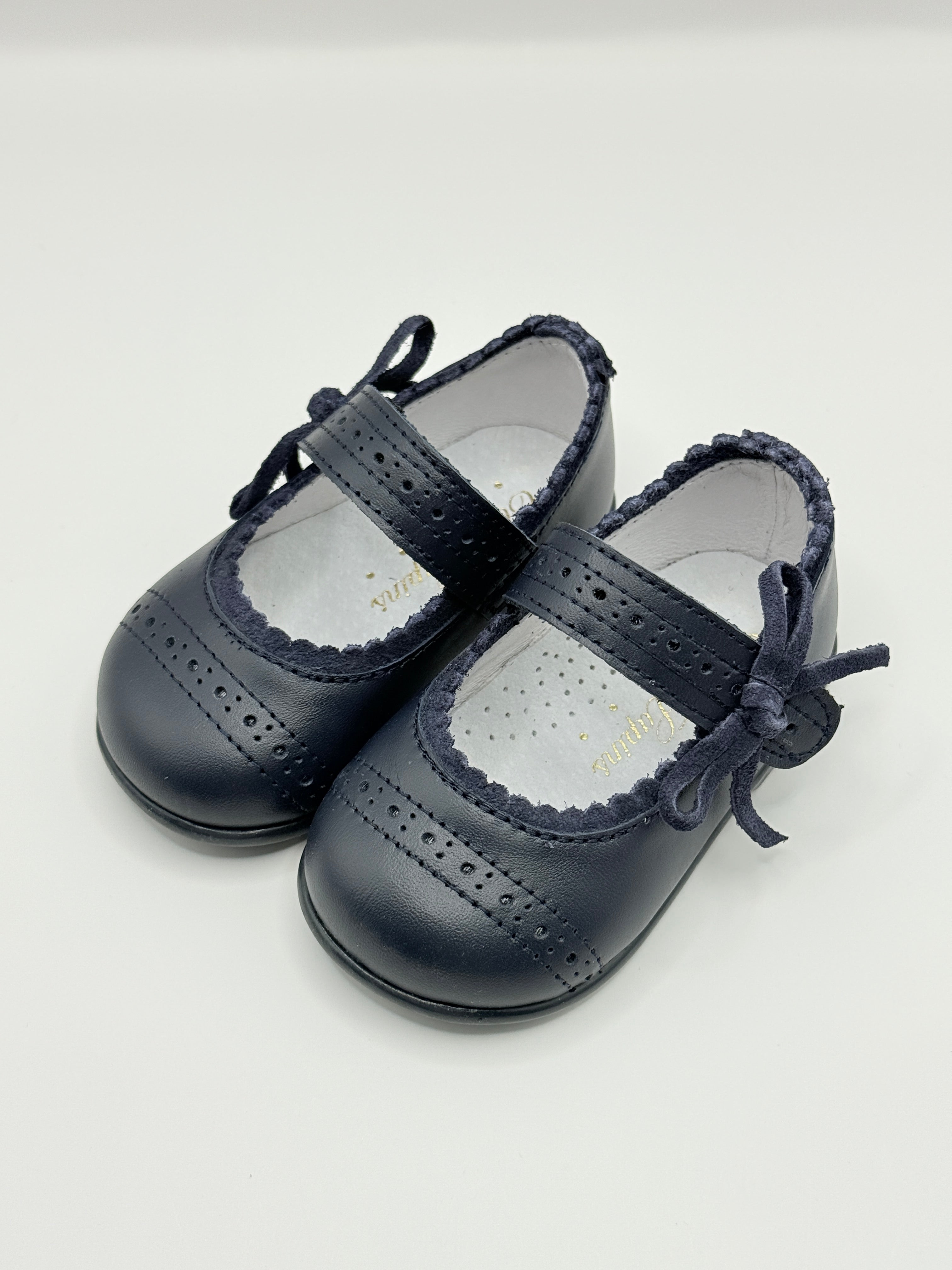 Pair of navy blue baby shoes with lace-up design on a light gray background