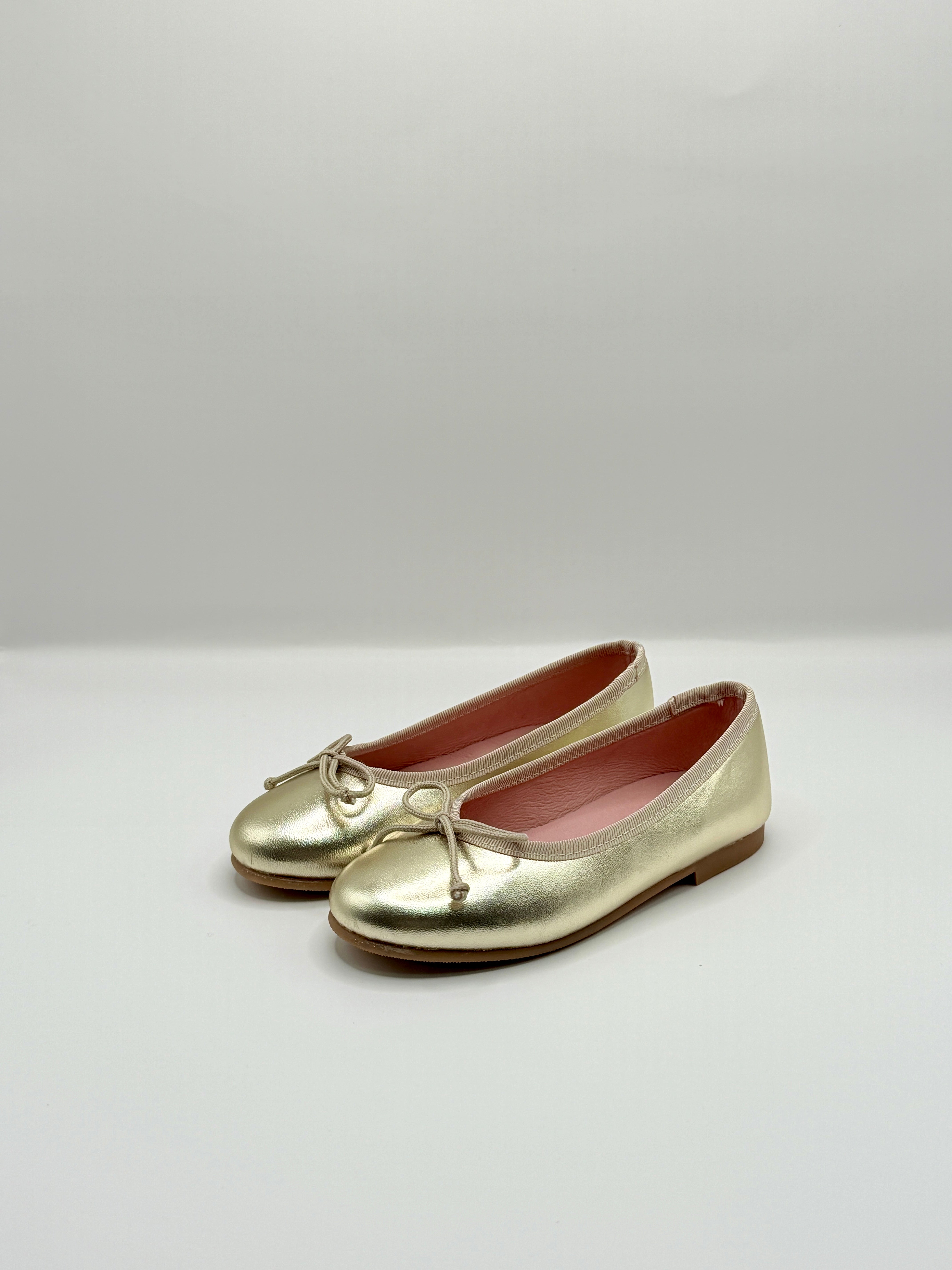 Gold shoes with a bow on a white background