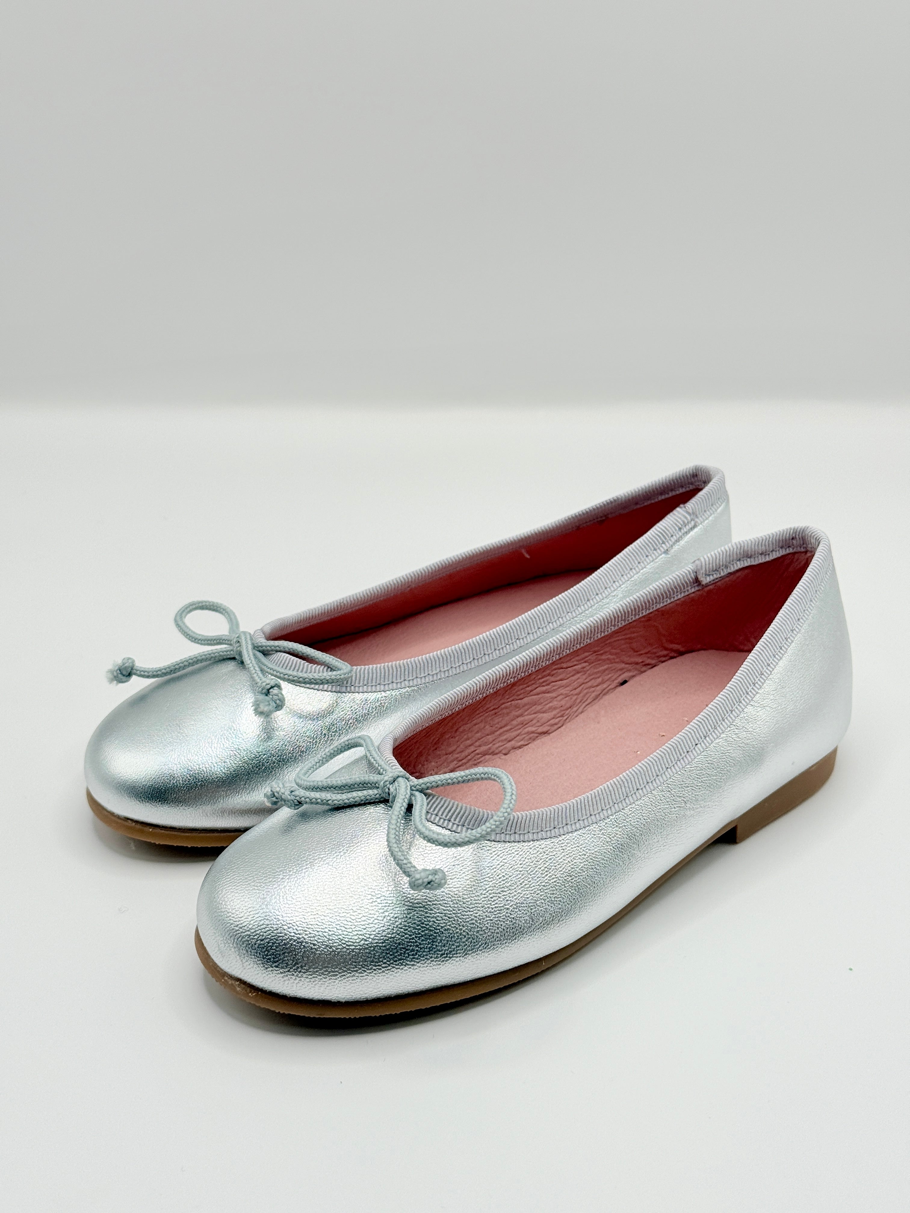 Silver shoes with pink lining on a white background