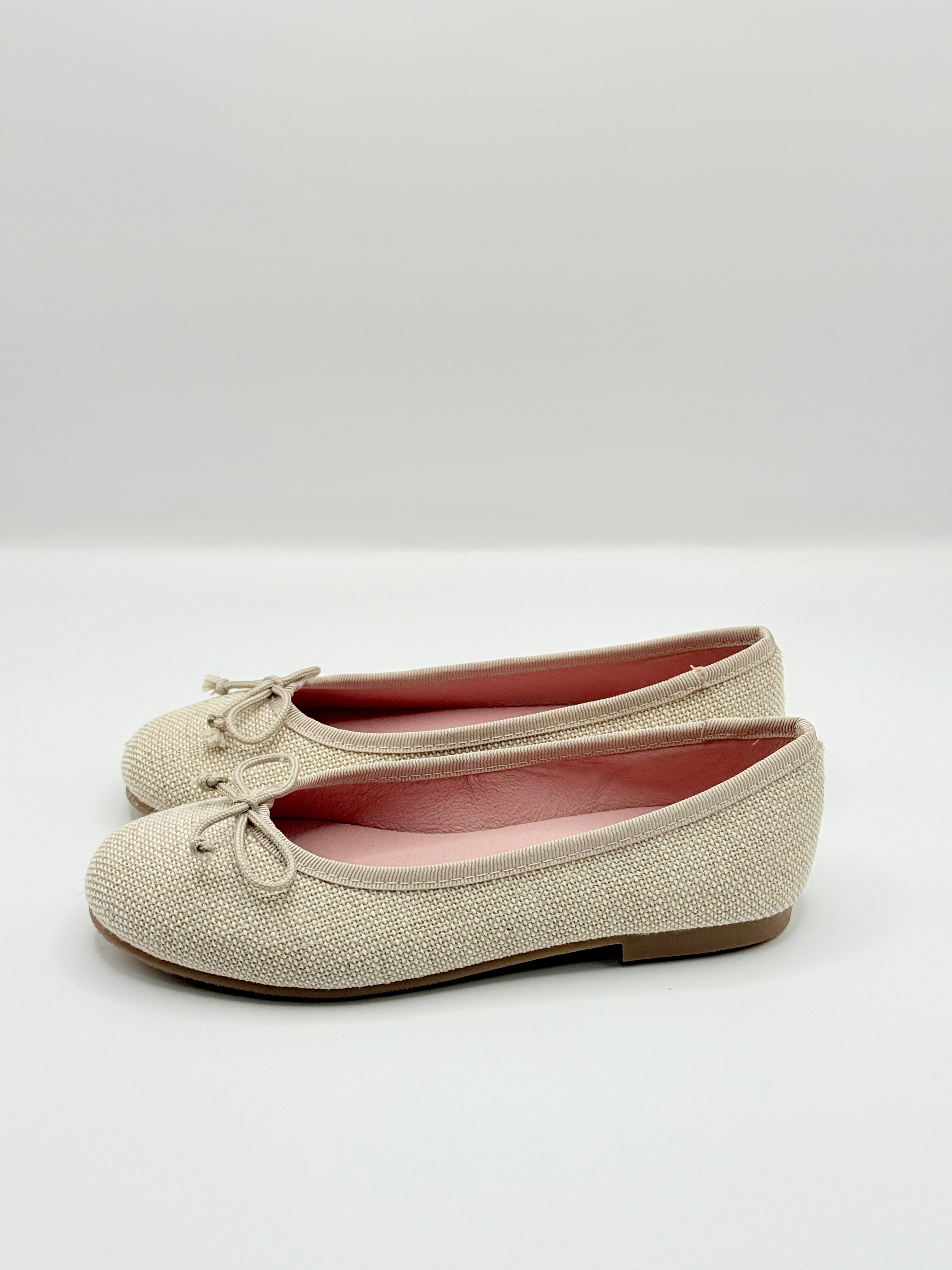 Pair of beige ballerina shoes on a light gray background