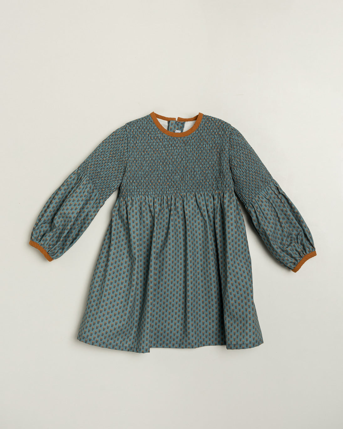 Green patterned dress with brown trim on a light gray background