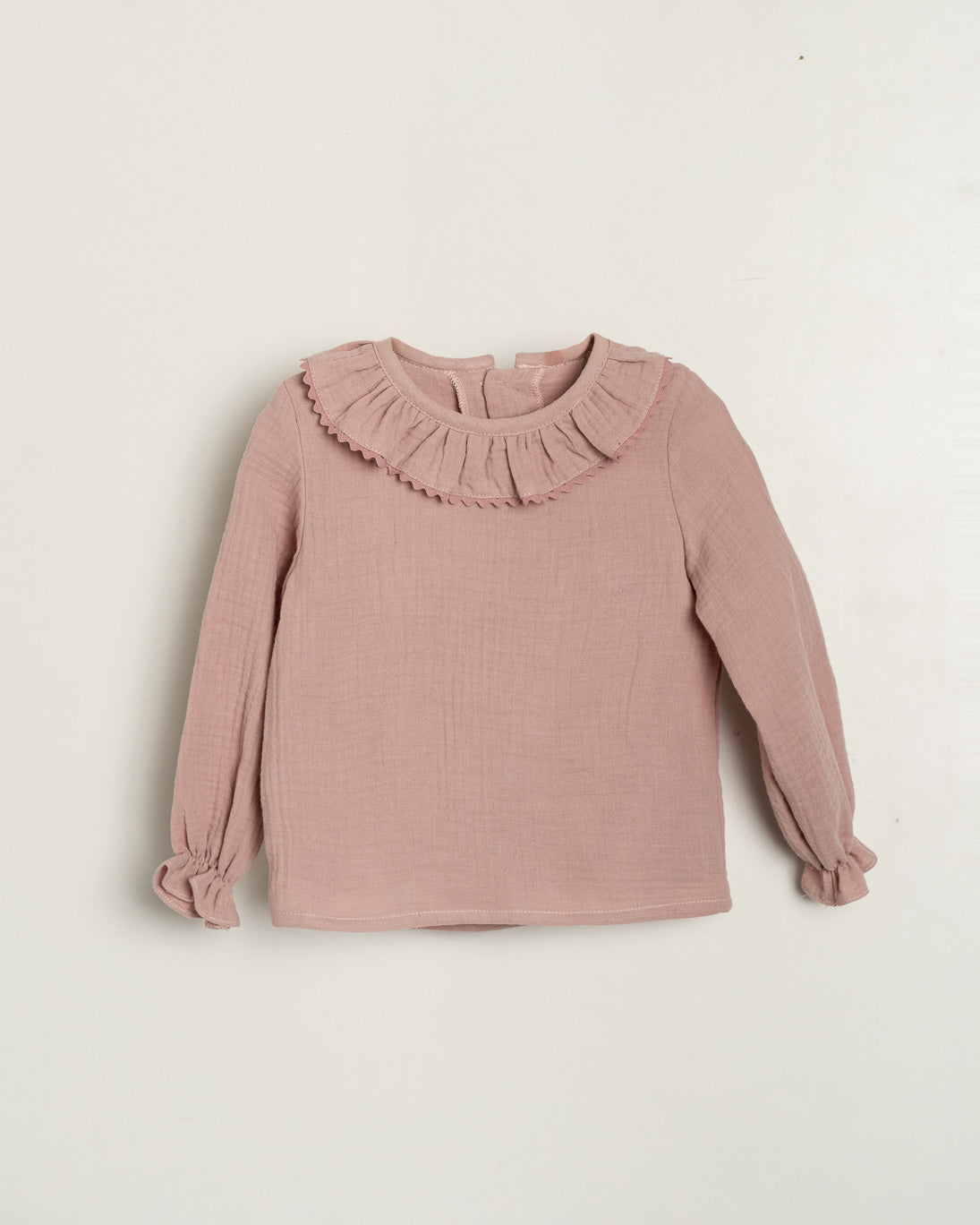 Pink blouse with ruffled collar on a light beige background