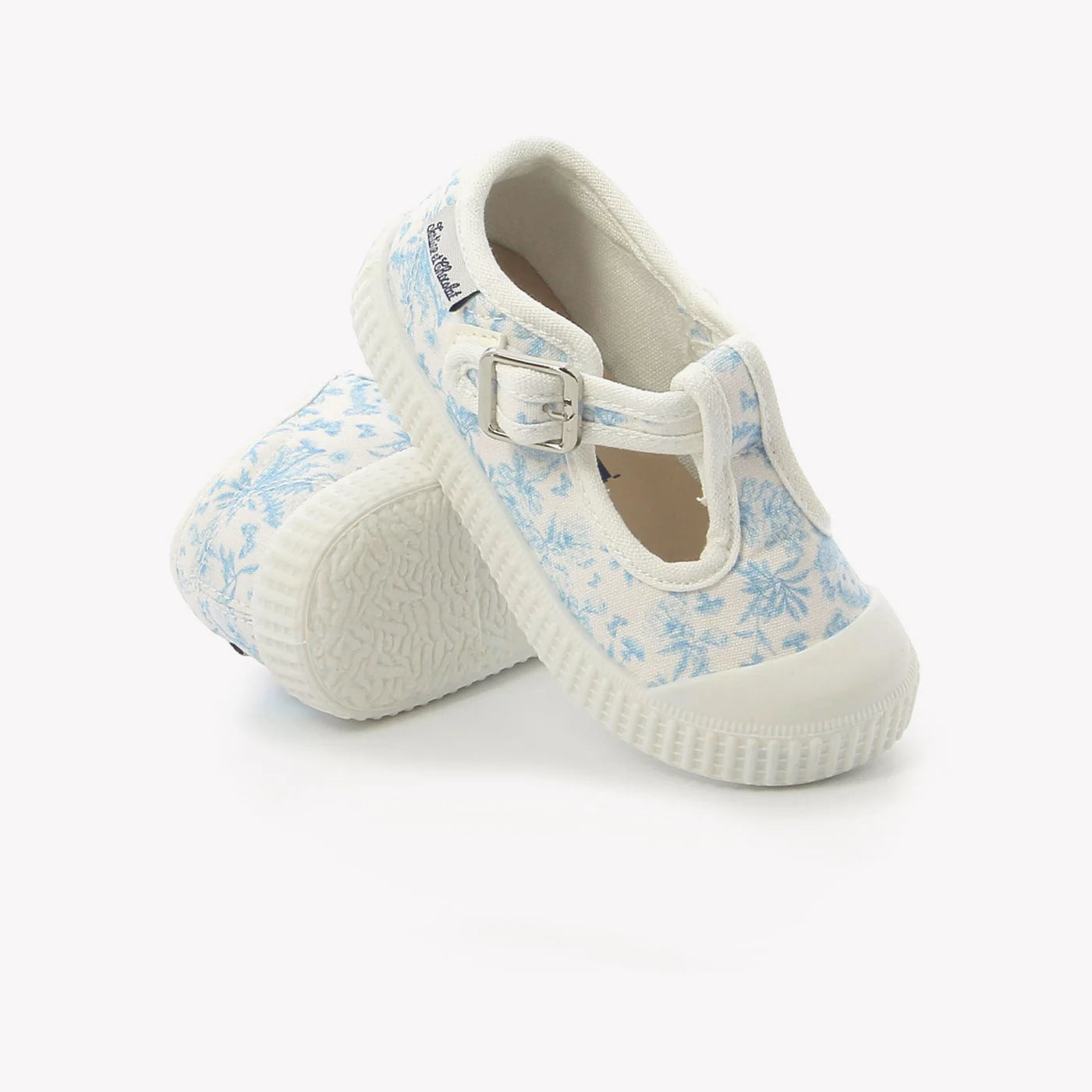 White children's shoes with blue floral pattern on a white background