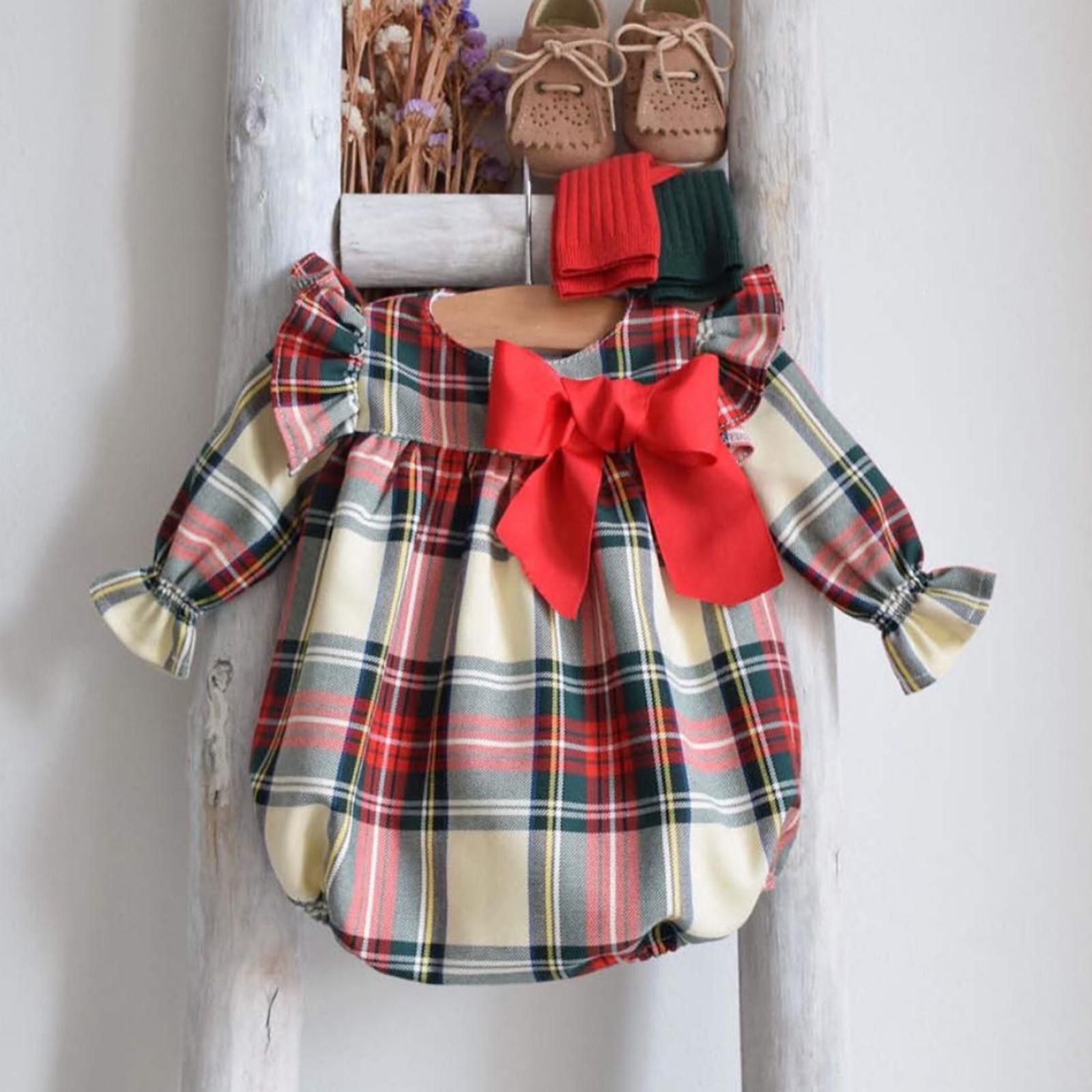 Plaid baby outfit with a red bow and matching shoes on a white background