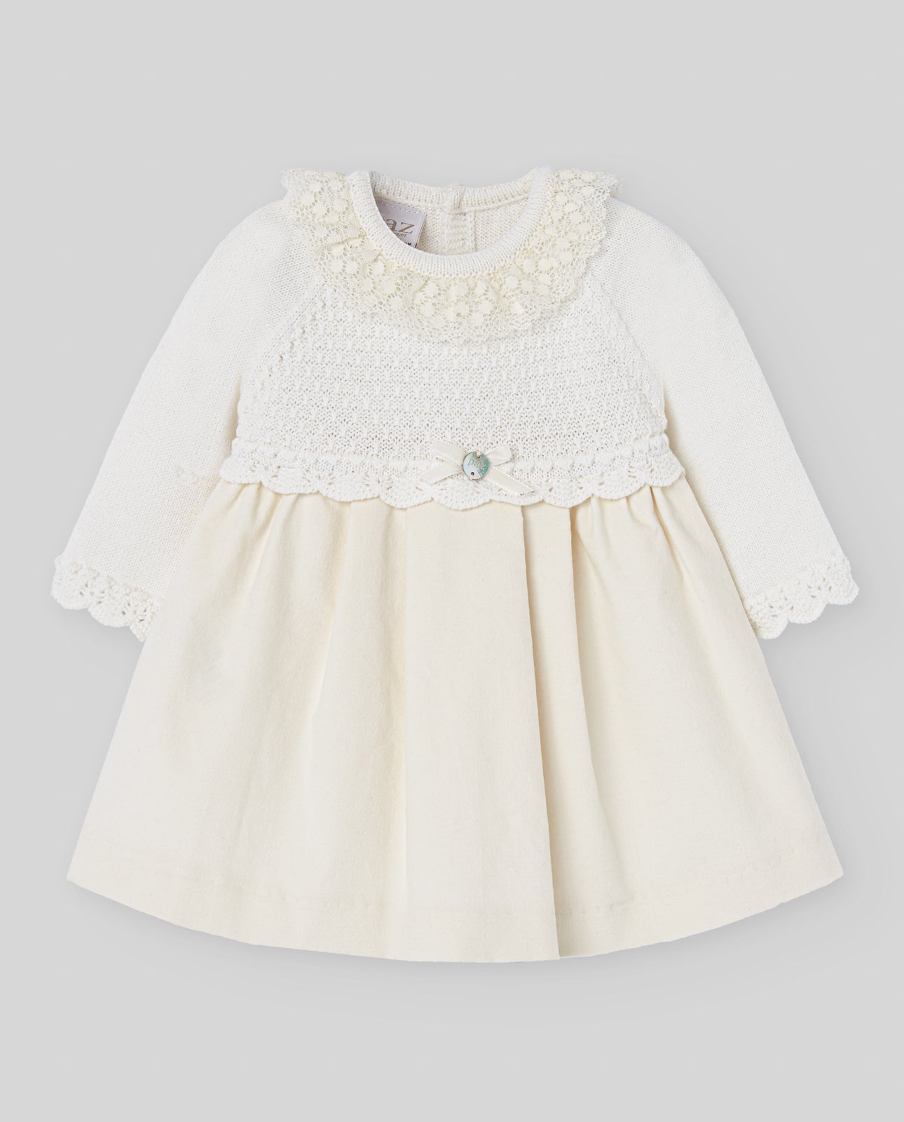 White baby dress with lace details on a gray background