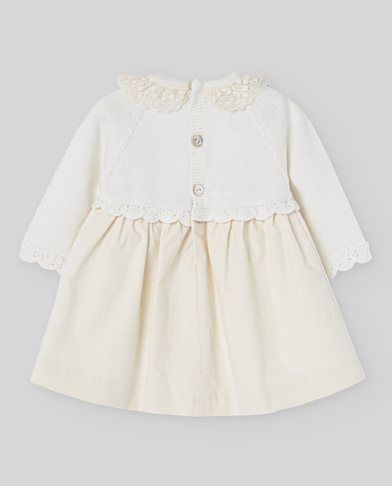 White baby dress with lace details on a gray background