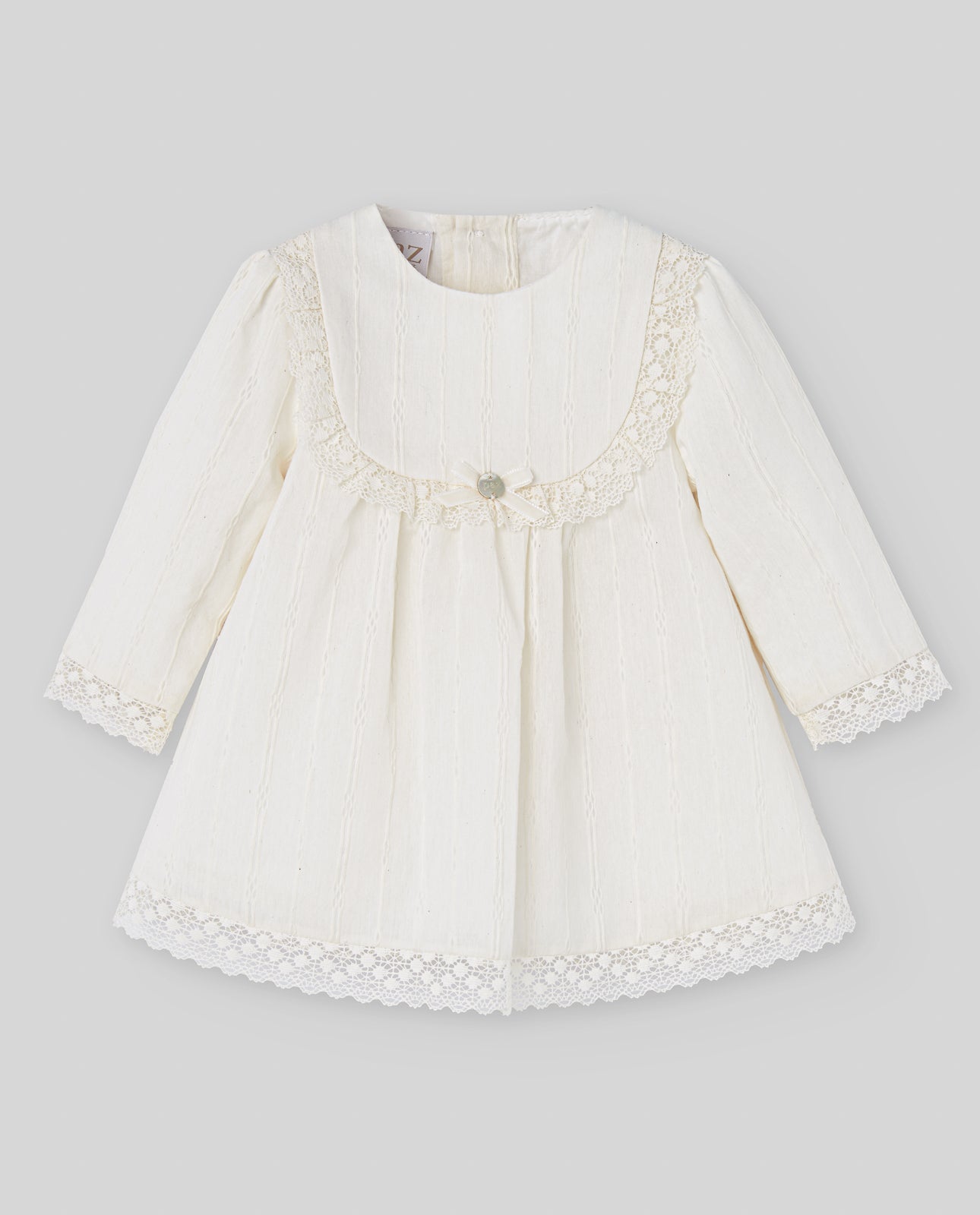 White baby dress with lace details on a gray background