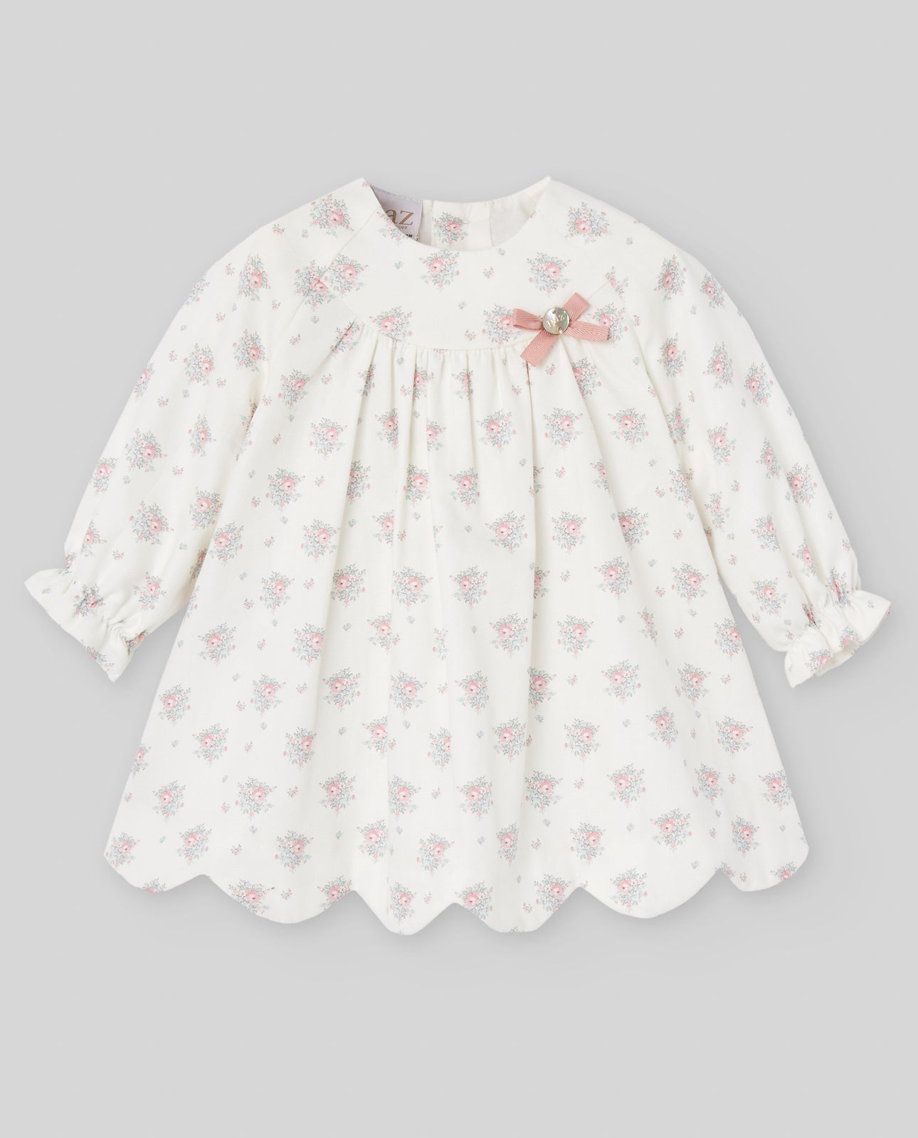 White dress with pink floral pattern on a gray background