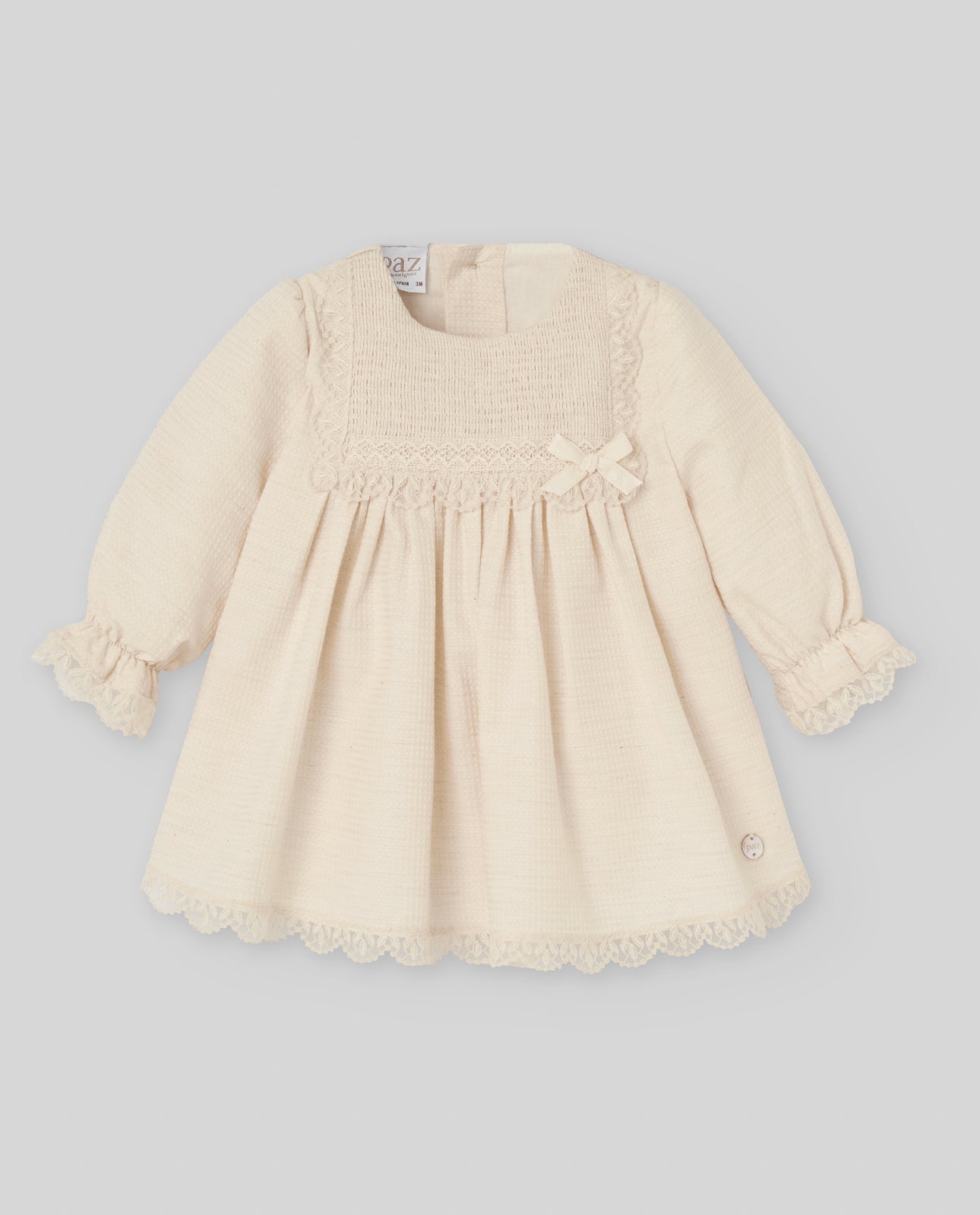 Beige baby dress with lace details on a light gray background