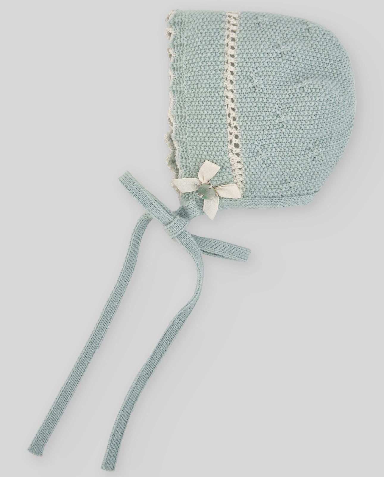 Light blue knitted baby bonnet with white trim on a light gray background