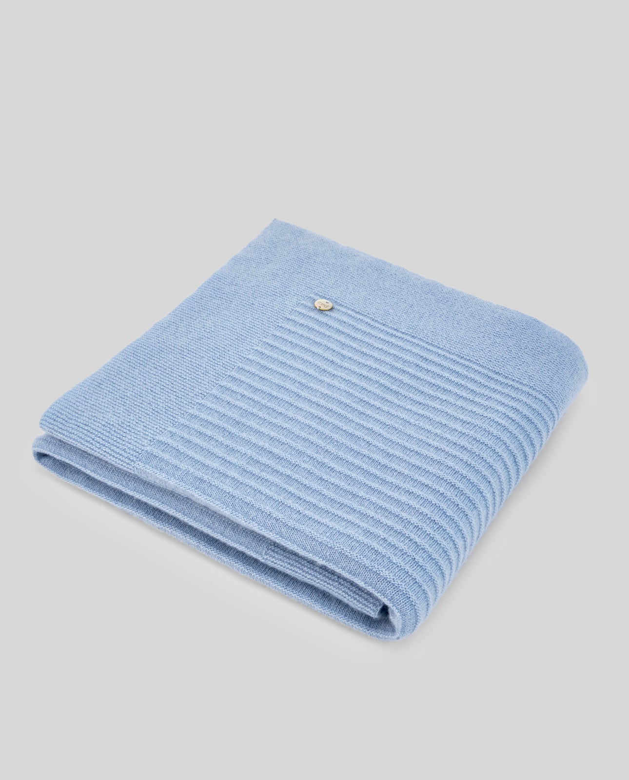 Folded light blue knitted blanket on a gray background