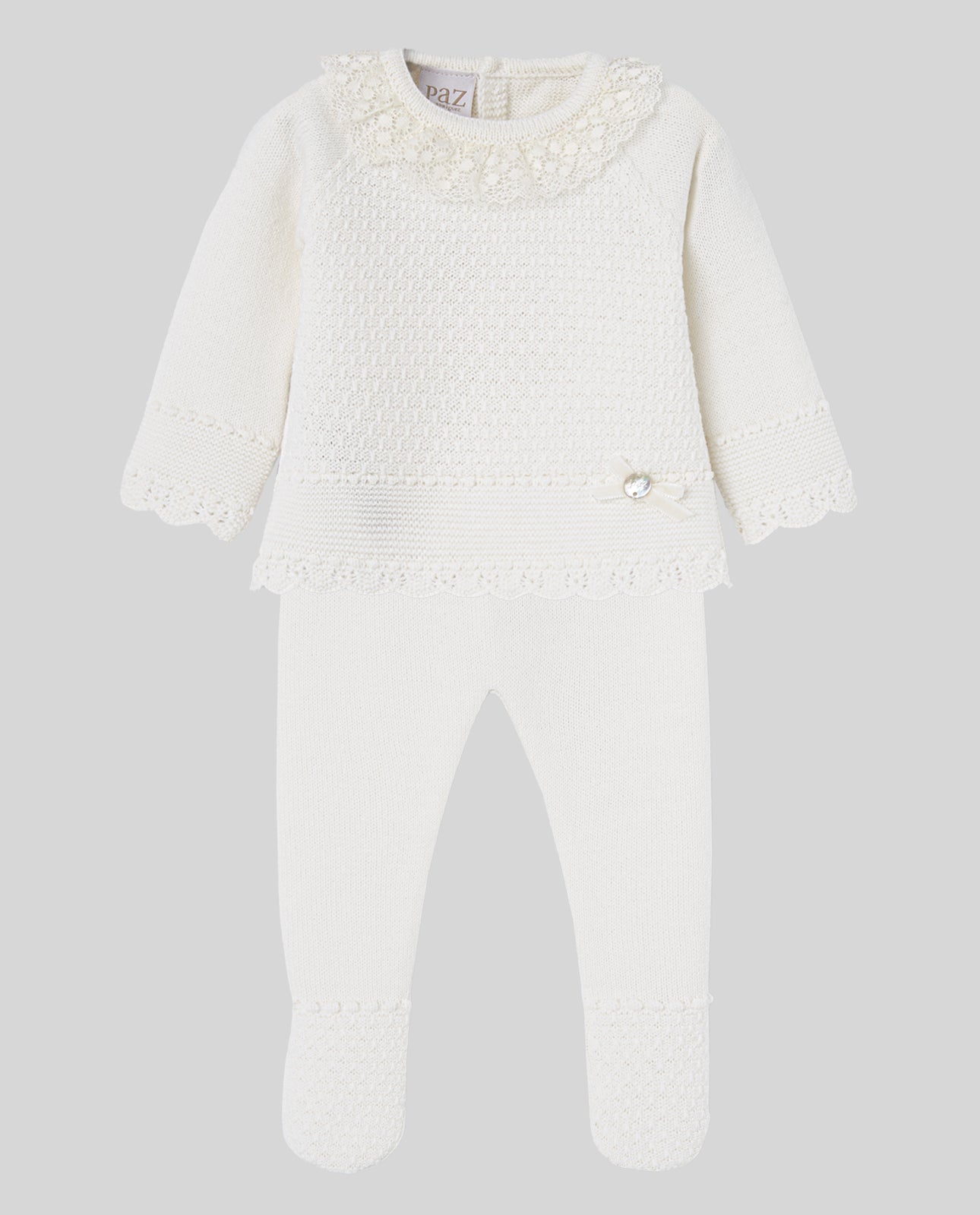 White baby set with lace details on a light gray background