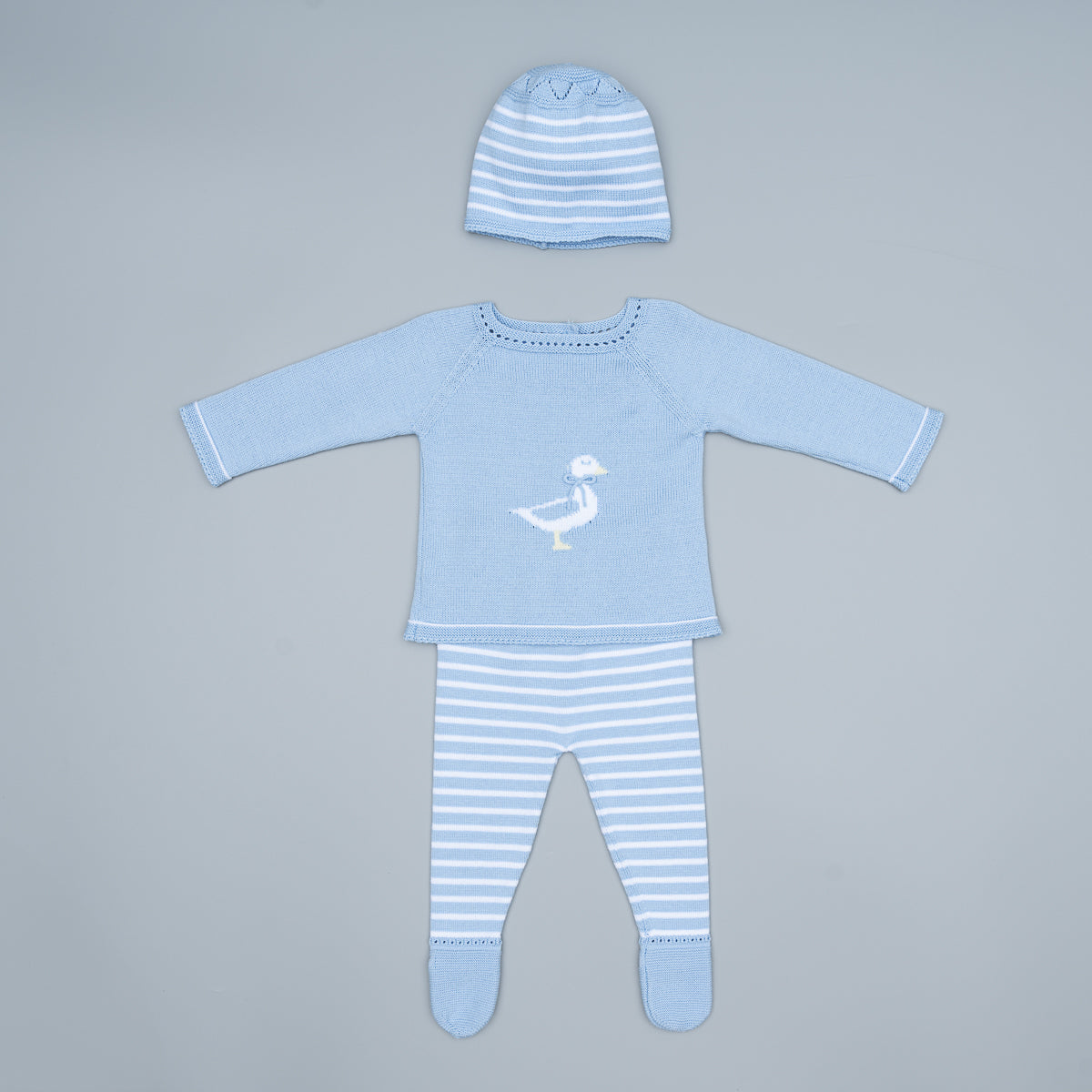Baby outfit set with blue long-sleeve shirt, striped pants, and hat on a gray background