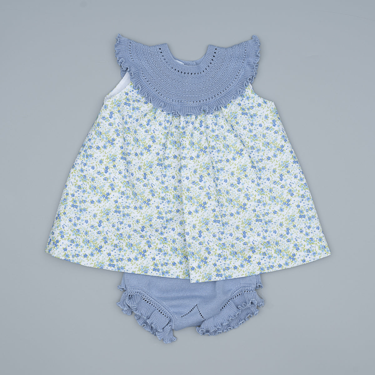 Baby dress with floral pattern and matching bloomers on a gray background