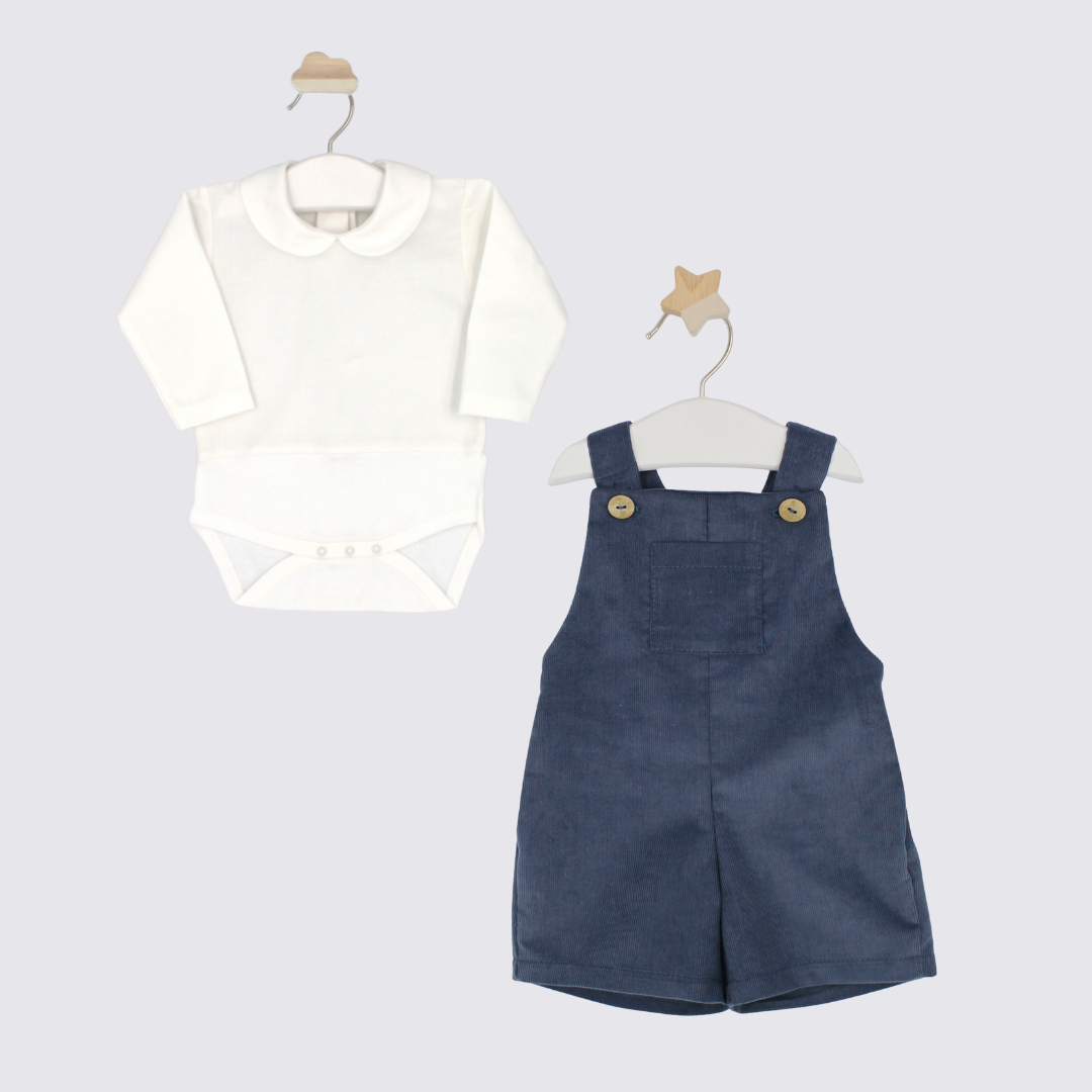 White shirt with a bow and blue denim overalls on hangers against a light gray background