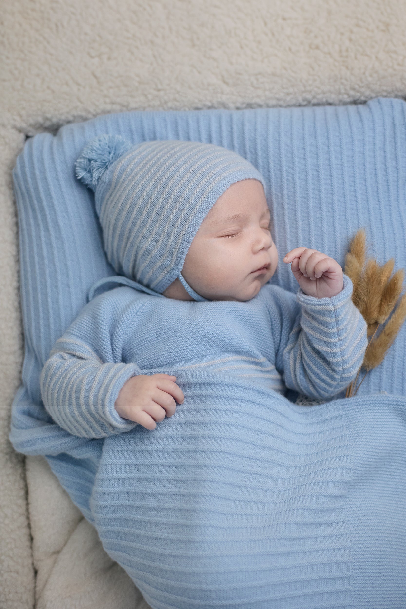 Newborn baby wrapped in a blue blanket and bonnet, sleeping peacefully.