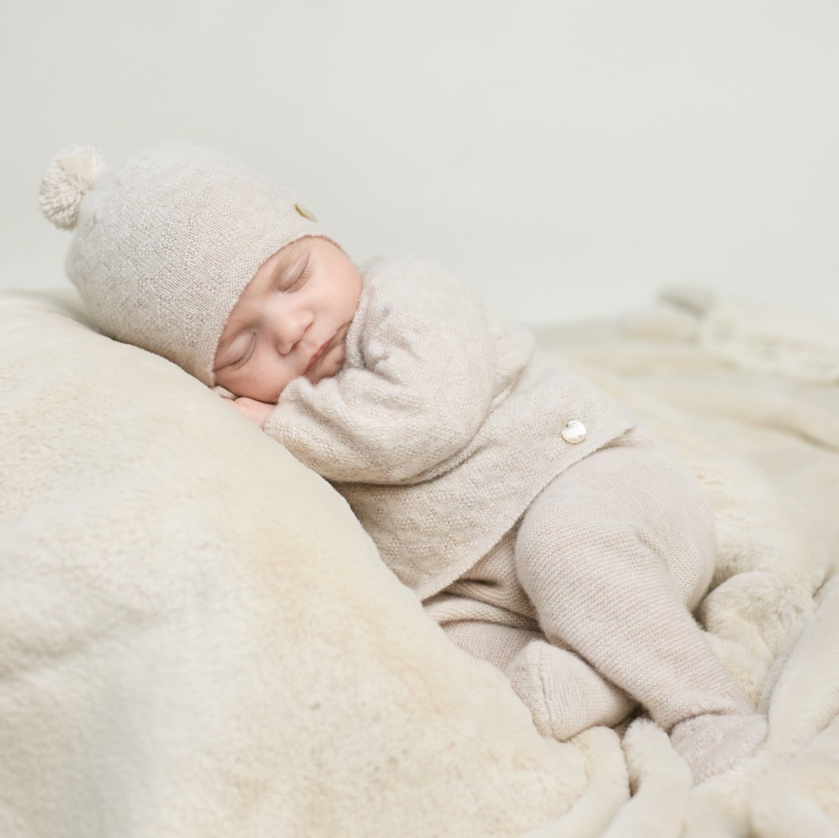 Baby sleeping in a cozy setting with soft textures and neutral colors