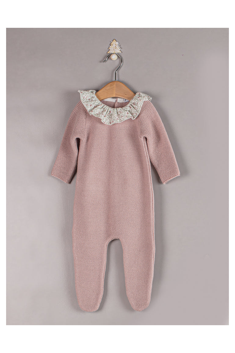 Pink baby onesie with lace collar on a hanger against a gray background