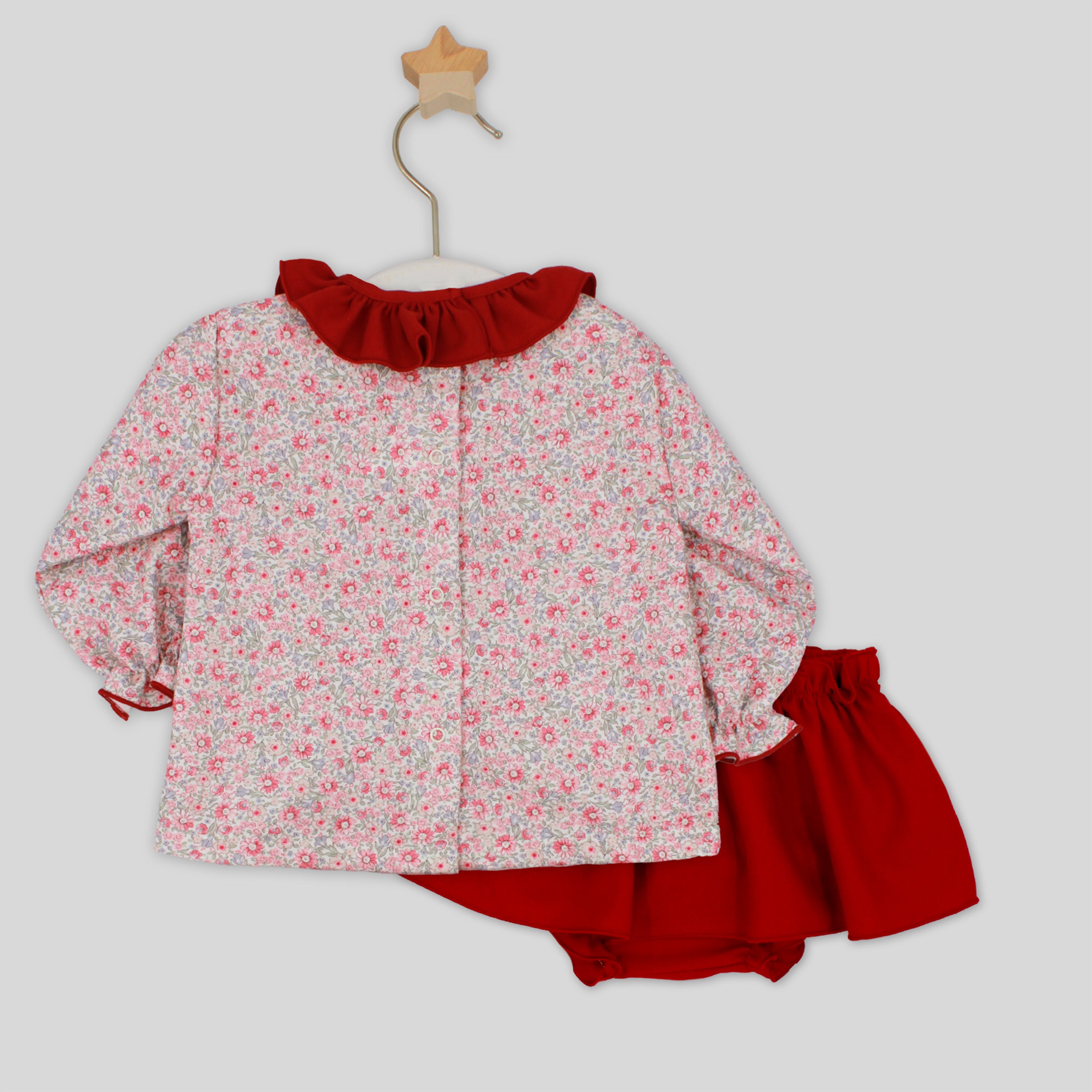 Children's outfit with floral top and red shorts on a white background