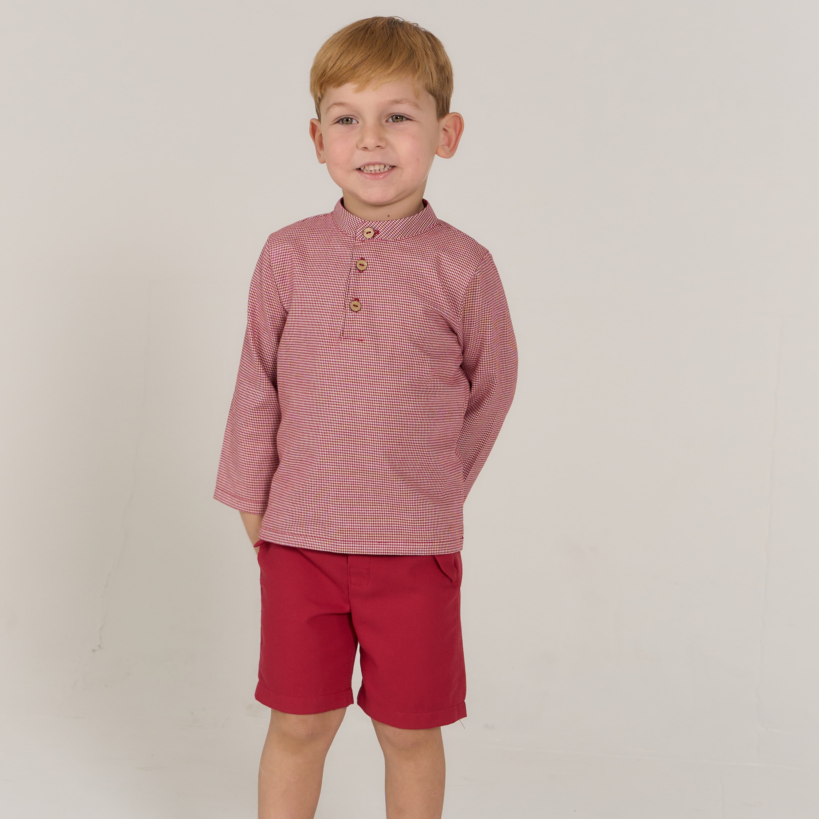 toddler boy in red shirt with red shorts.