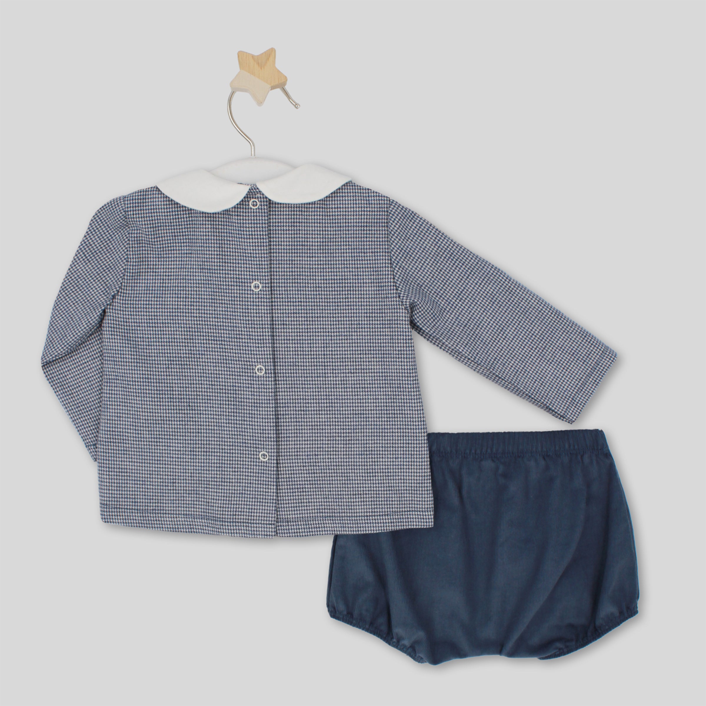 Baby outfit with checkered shirt and navy bloomers on a light gray background