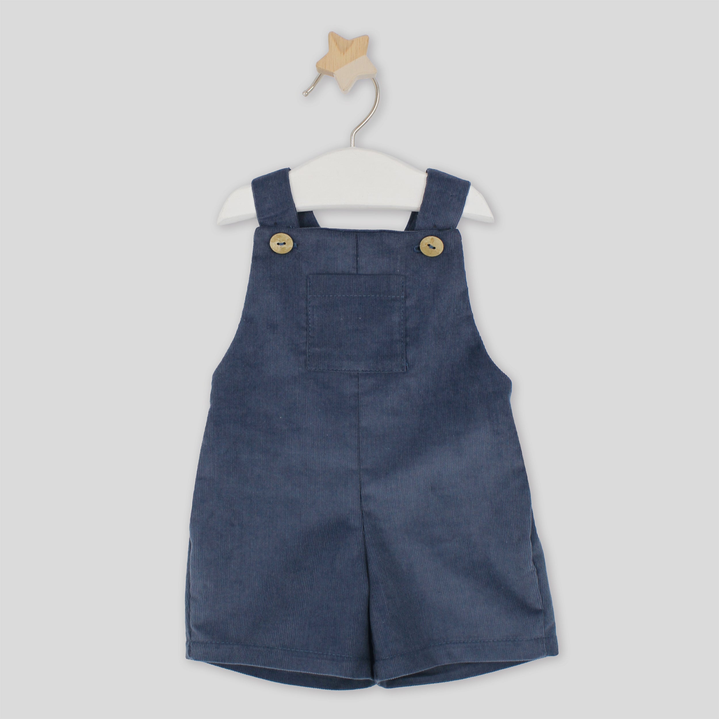 Blue denim overalls on a white hanger against a white background